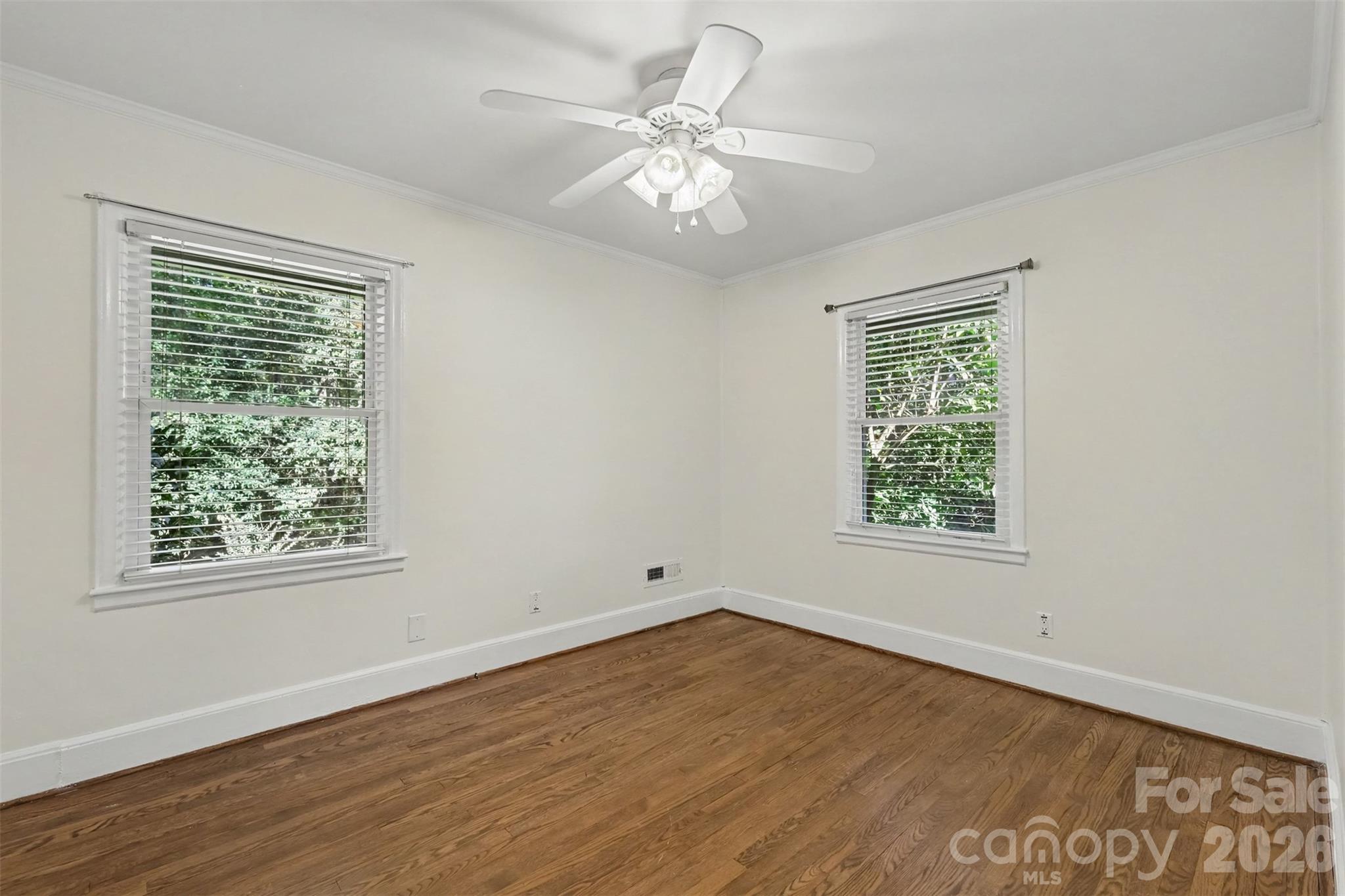 The guest bedroom without furniture, showing its hardwood floors, windows, and available space. - 407 Pine Street, Fort Mill