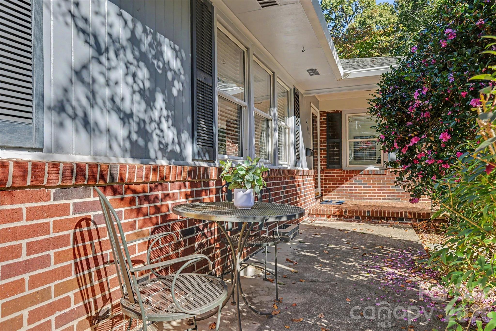 A charming front patio nook tucked among the established landscaping. Just add your morning coffee! - 407 Pine Street, Fort Mill