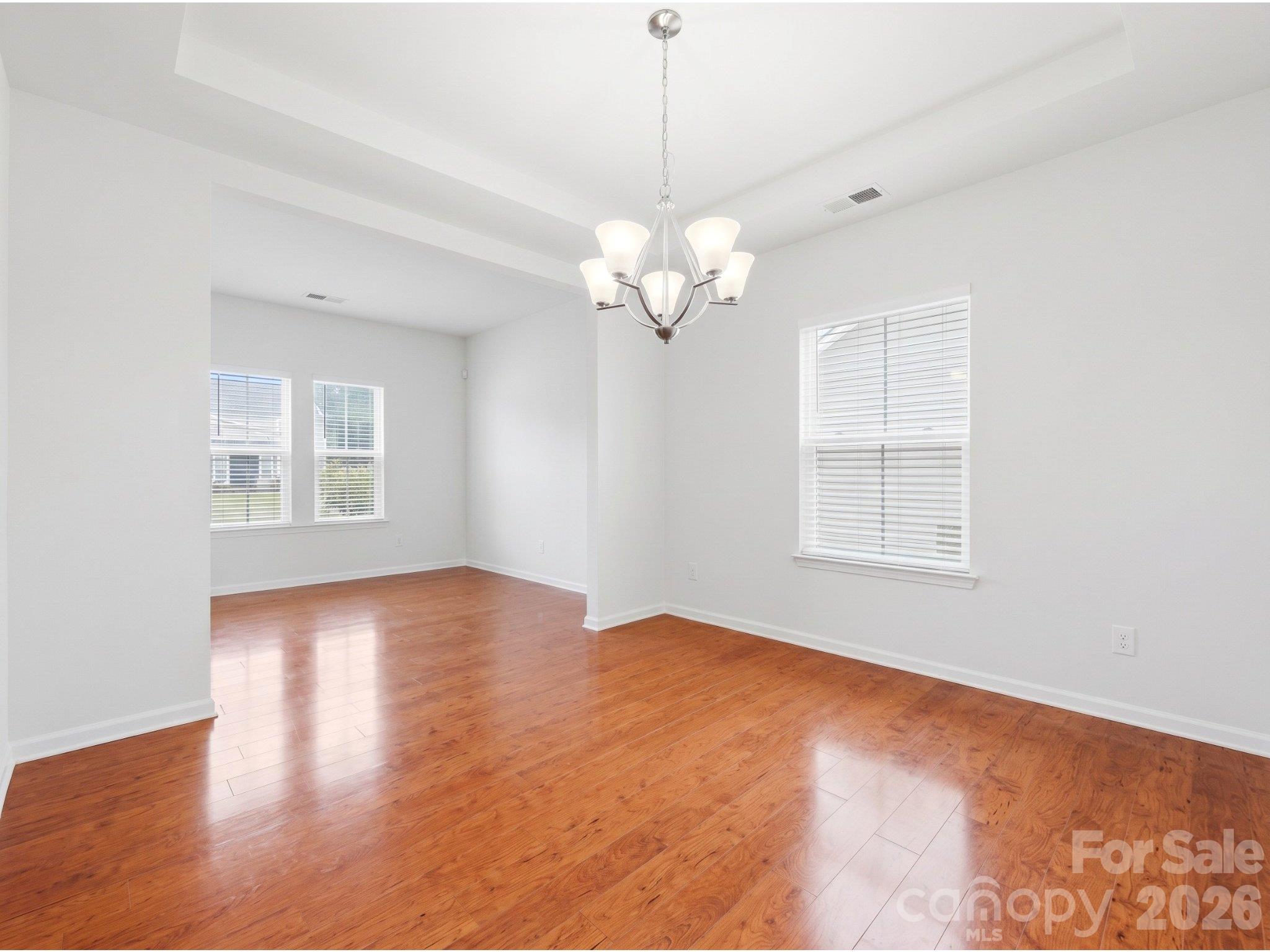 Dining room: Unstaged view showing wood flooring, the existing chandelier, and the connection to the adjoining main-level flex space. - 3341 Linetender Drive, Davidson
