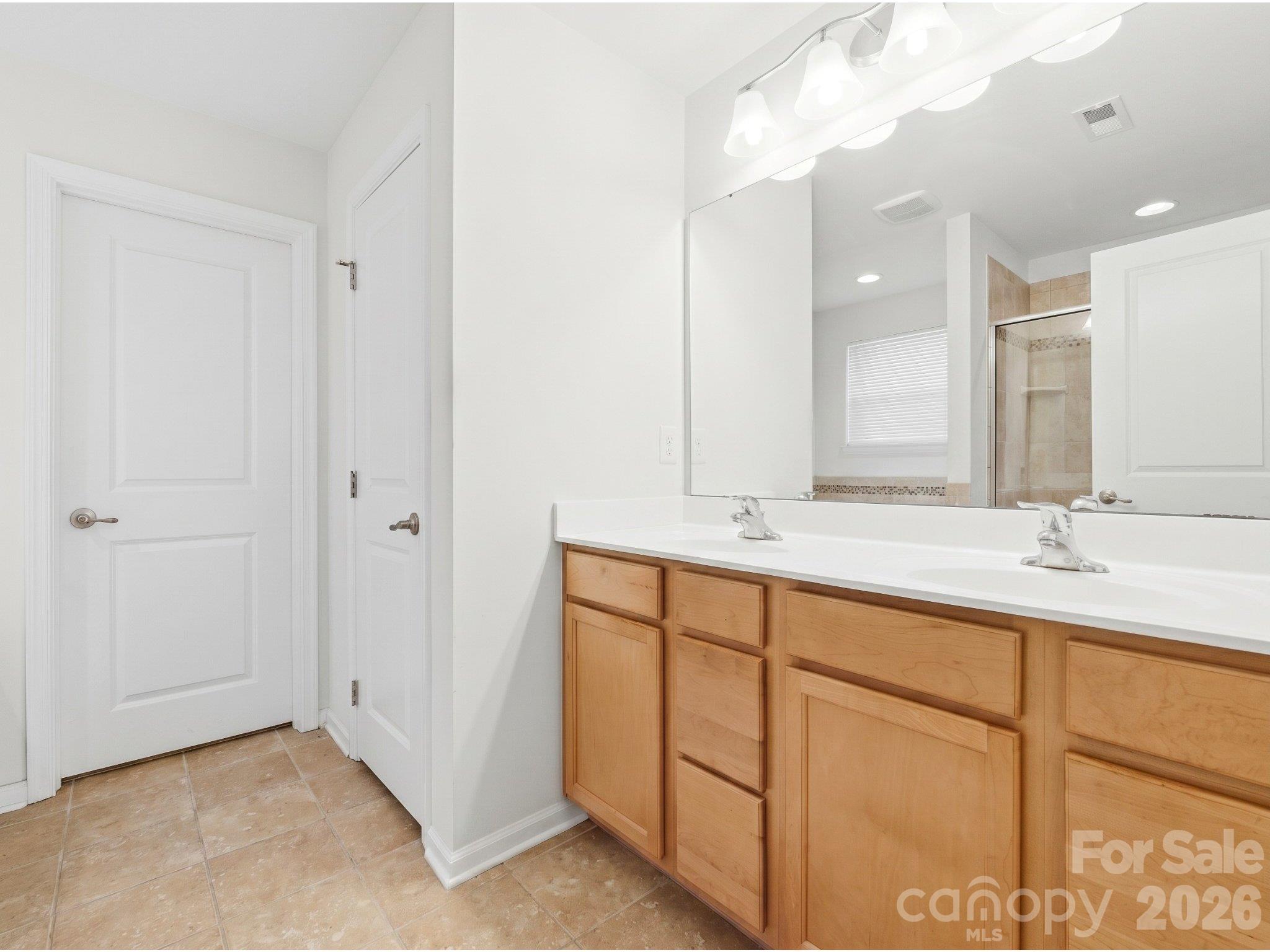 Primary ensuite: Dual-sink vanity with cabinet and drawer storage, plus access to a walk-in closet. - 3341 Linetender Drive, Davidson