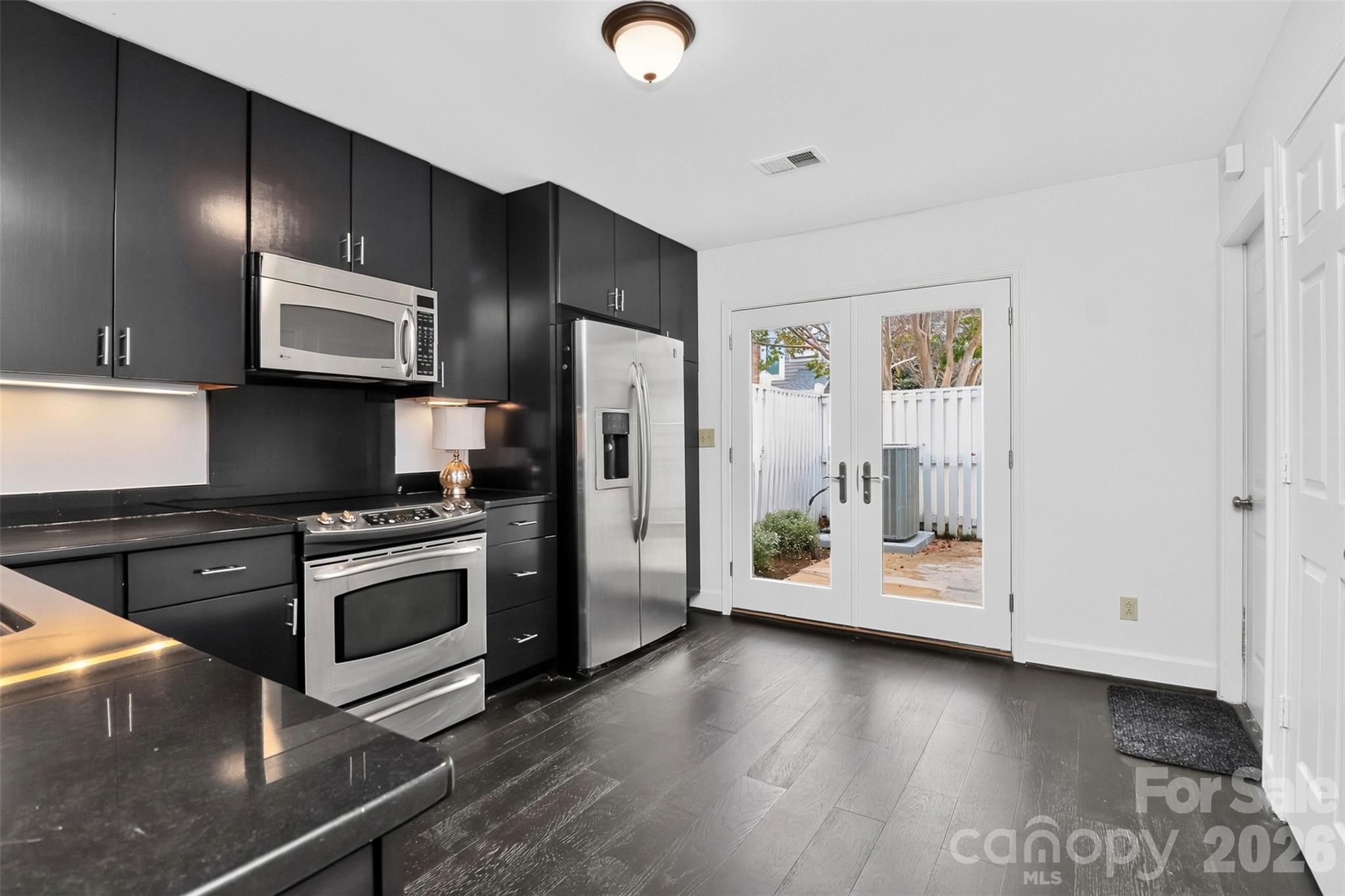Kitchen with doors to side patio, garage and laundry closet, washer and dryer remain - 8254 Tradd Court, Charlotte