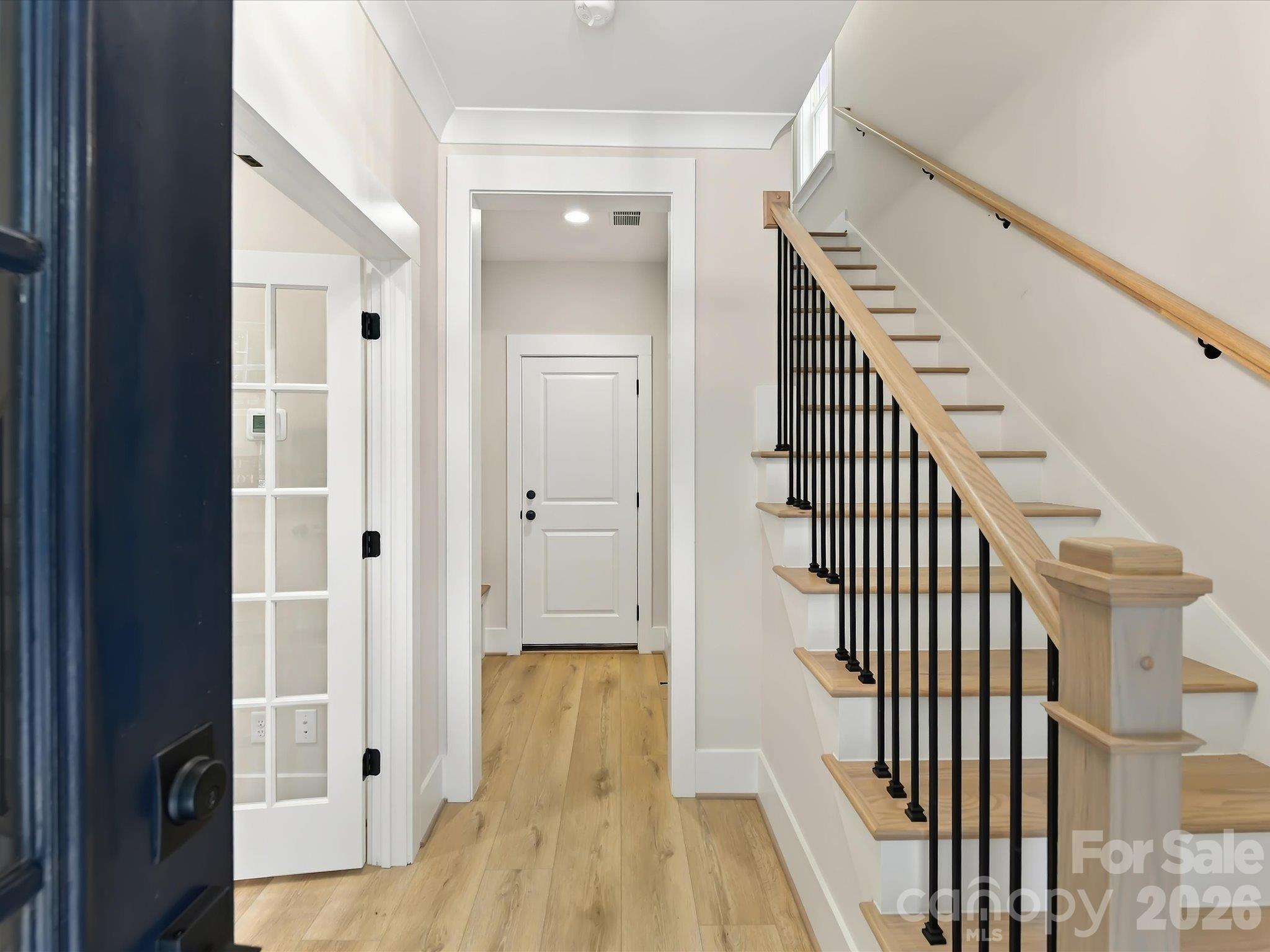 Welcoming foyer featuring beautiful LVP flooring, crisp white trim, and a stylish staircase with natural wood railings and black metal balusters. - 225 Davidson Gateway Drive, Davidson