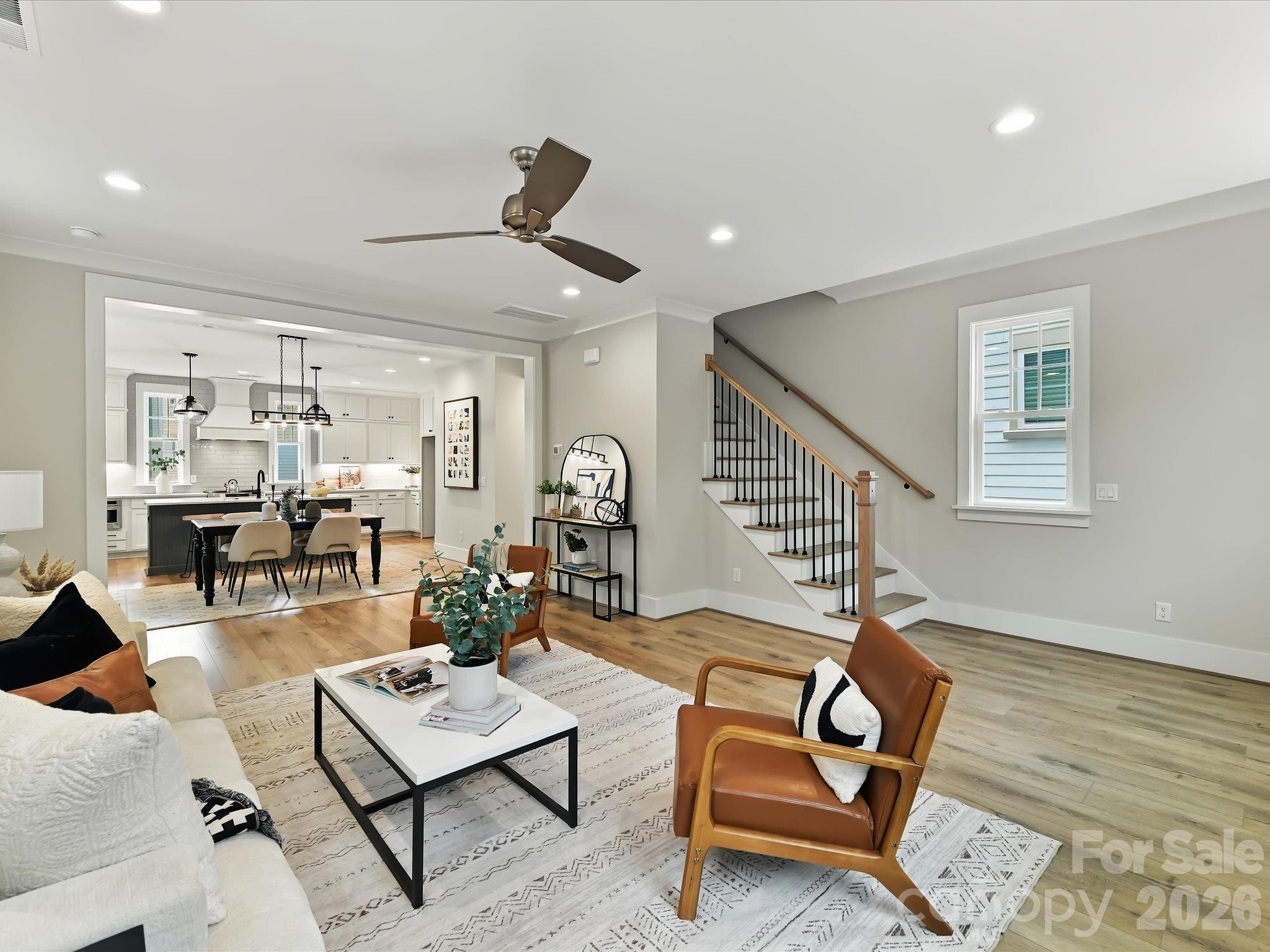 Spacious family room featuring an open-concept layout, beautiful LVP flooring, abundant natural light, and seamless flow into the dining area and kitchen. - 225 Davidson Gateway Drive, Davidson