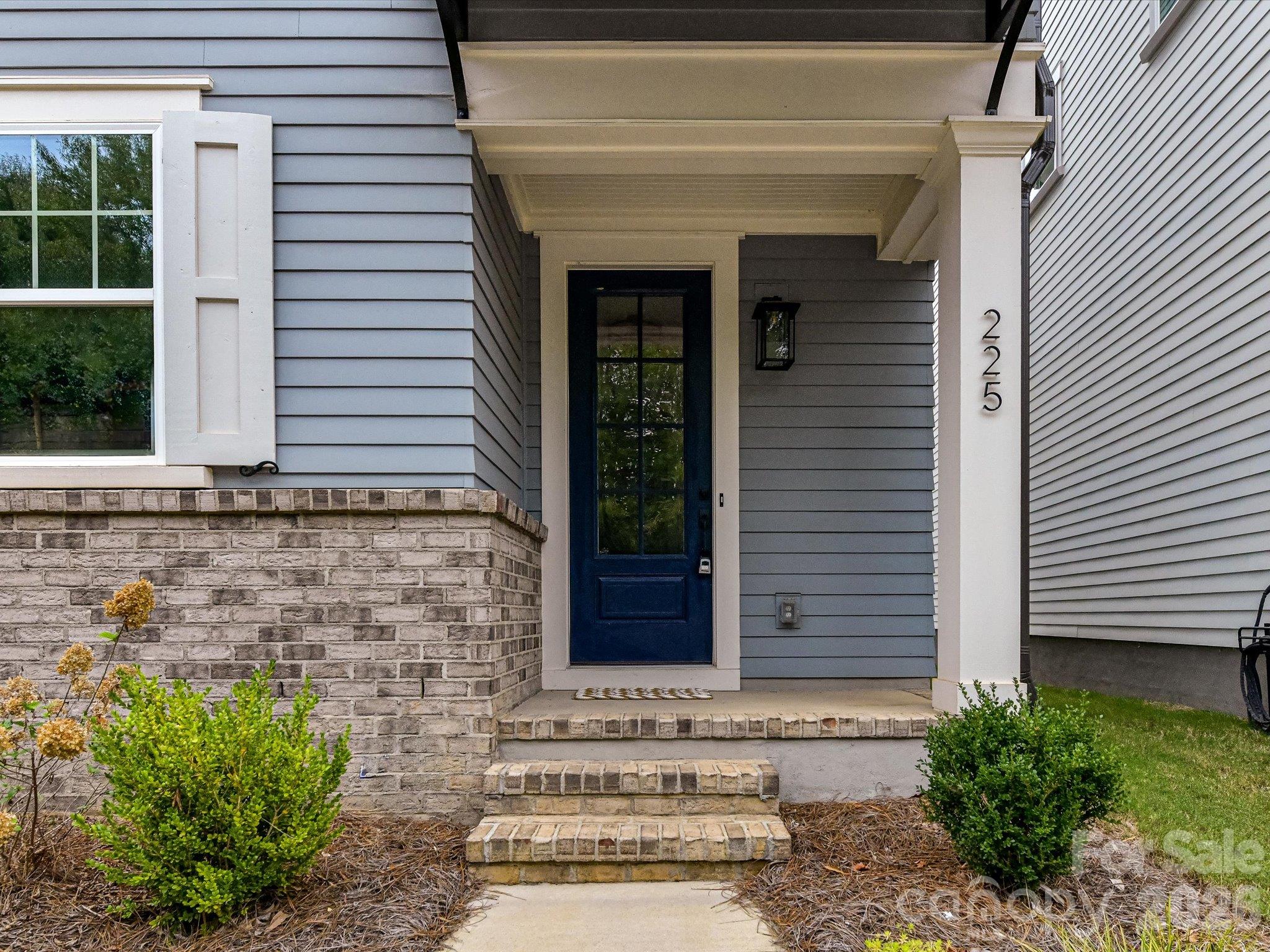 Welcoming covered front entrance featuring a stylish front door, classic brick accents, and attractive landscaping that creates inviting curb appeal. - 225 Davidson Gateway Drive, Davidson