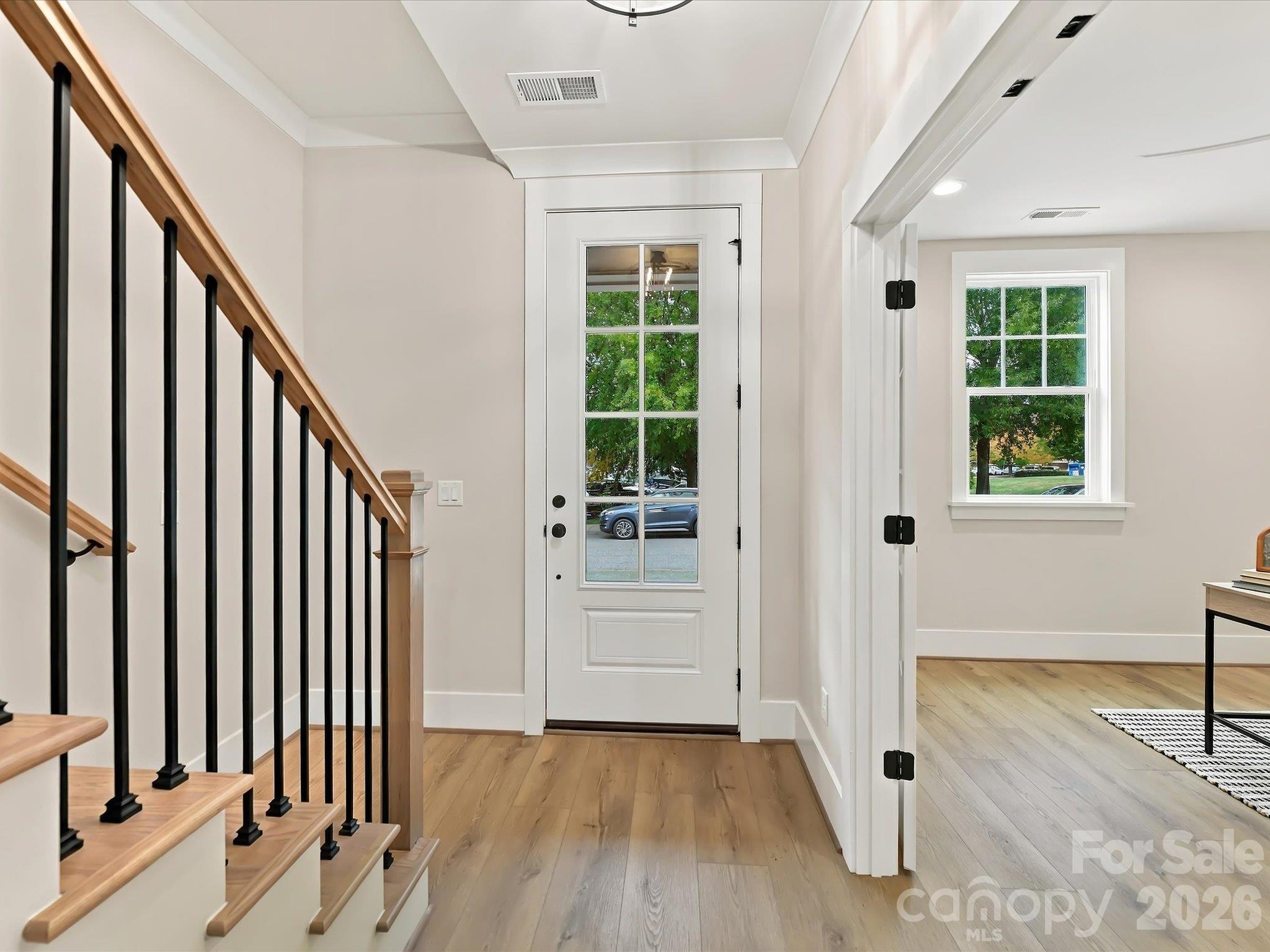 Welcoming foyer featuring beautiful LVP flooring, crisp white trim, and a stylish staircase with natural wood railings and black metal balusters. - 225 Davidson Gateway Drive, Davidson