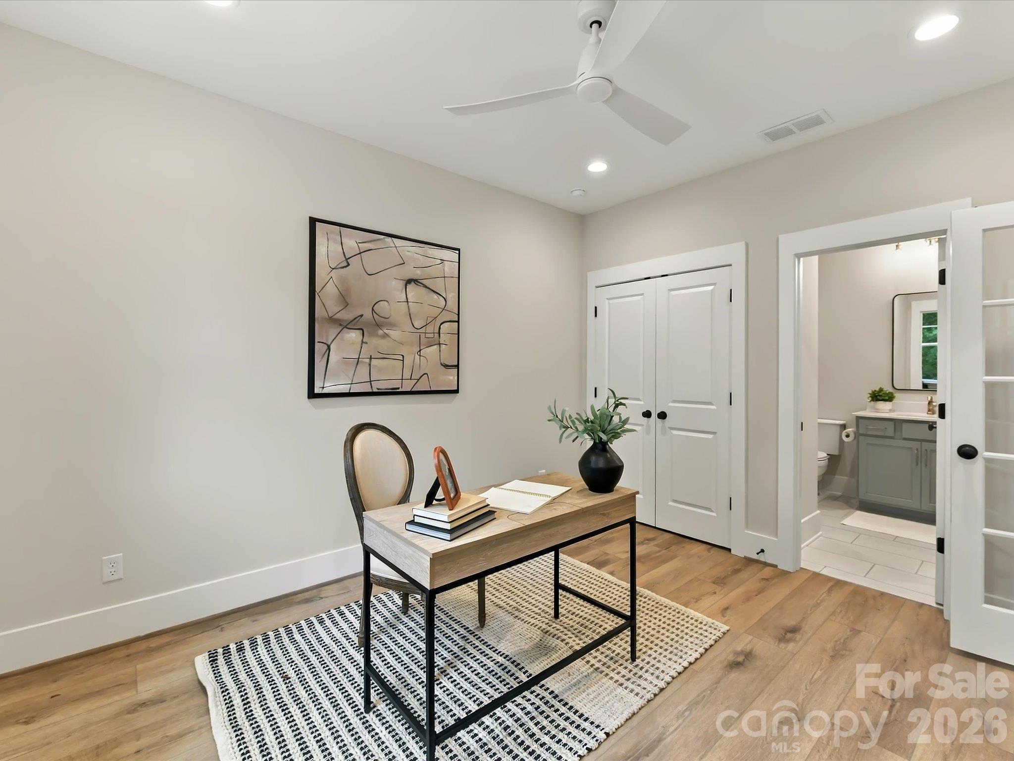 Versatile main-level office, bedroom or flex space featuring French doors, beautiful LVP, ample closet storage, and convenient access to a full bath. - 225 Davidson Gateway Drive, Davidson