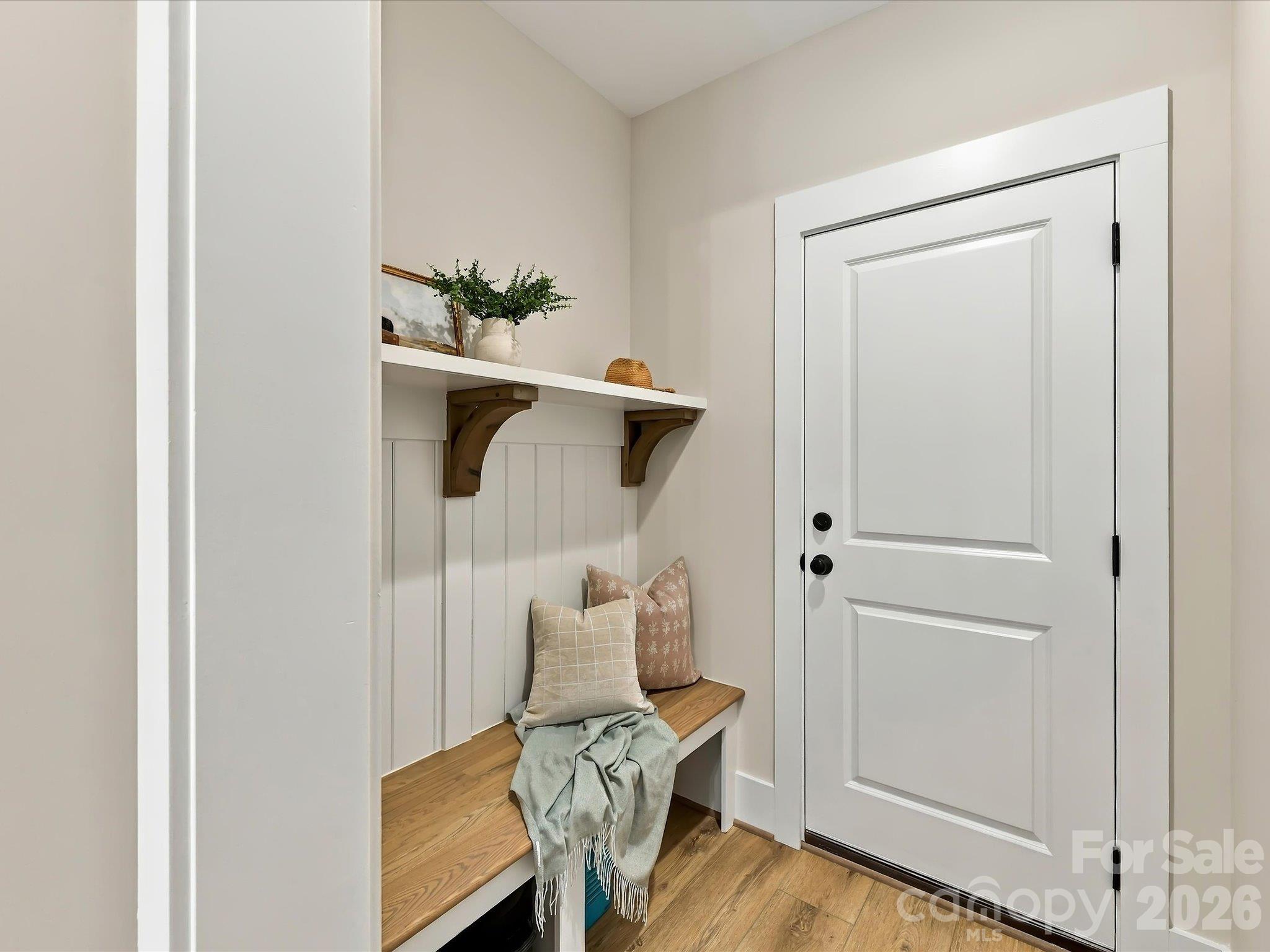 Convenient drop zone featuring a built-in wood bench, decorative wall paneling, and overhead shelving for everyday organization. - 225 Davidson Gateway Drive, Davidson