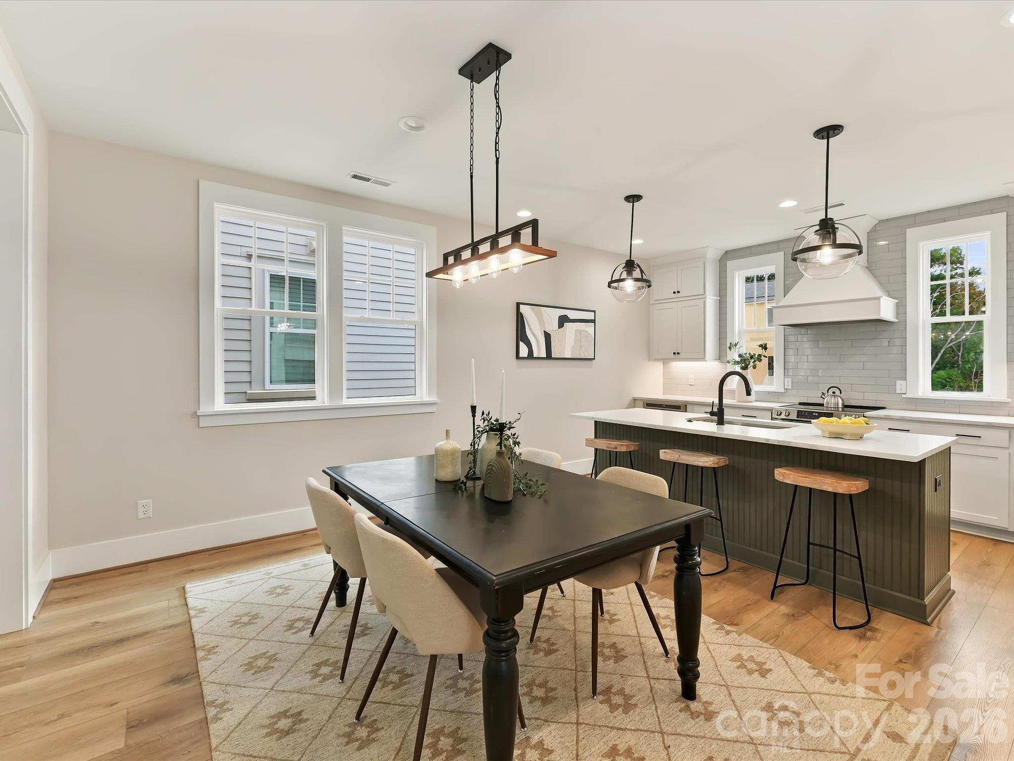 Elegant dining area featuring LVP flooring, modern statement lighting, and an open flow into the spacious kitchen and family room. - 225 Davidson Gateway Drive, Davidson