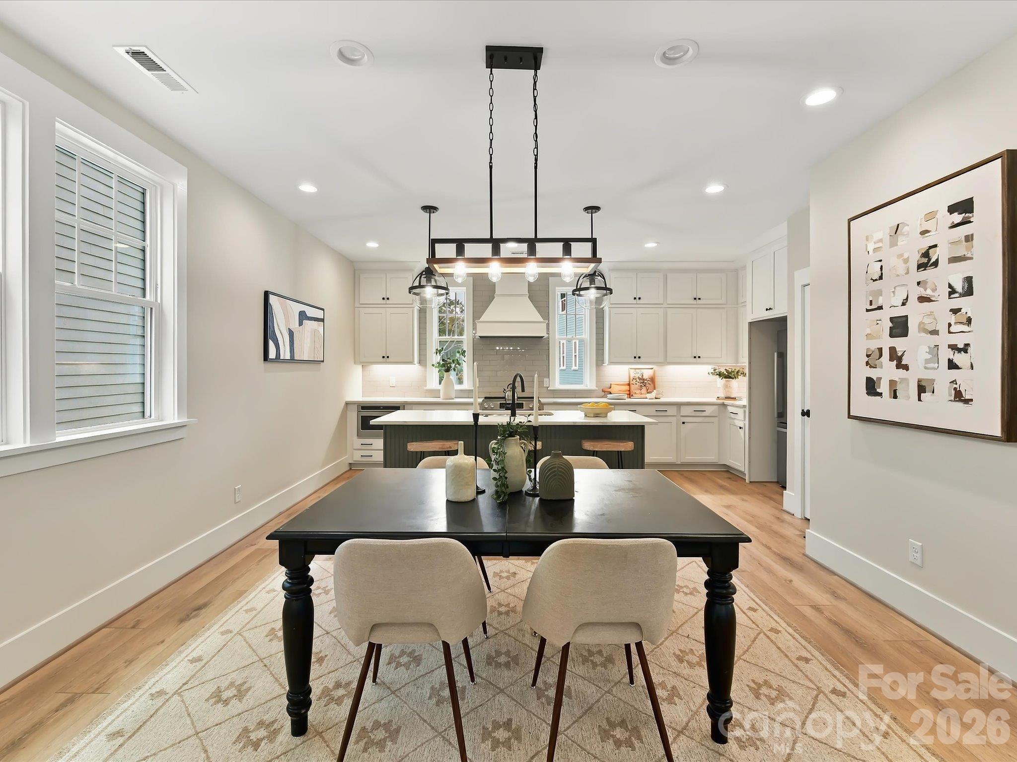 Elegant dining area featuring beautiful LVP flooring, modern statement lighting, and an open flow into the spacious kitchen and family room. - 225 Davidson Gateway Drive, Davidson