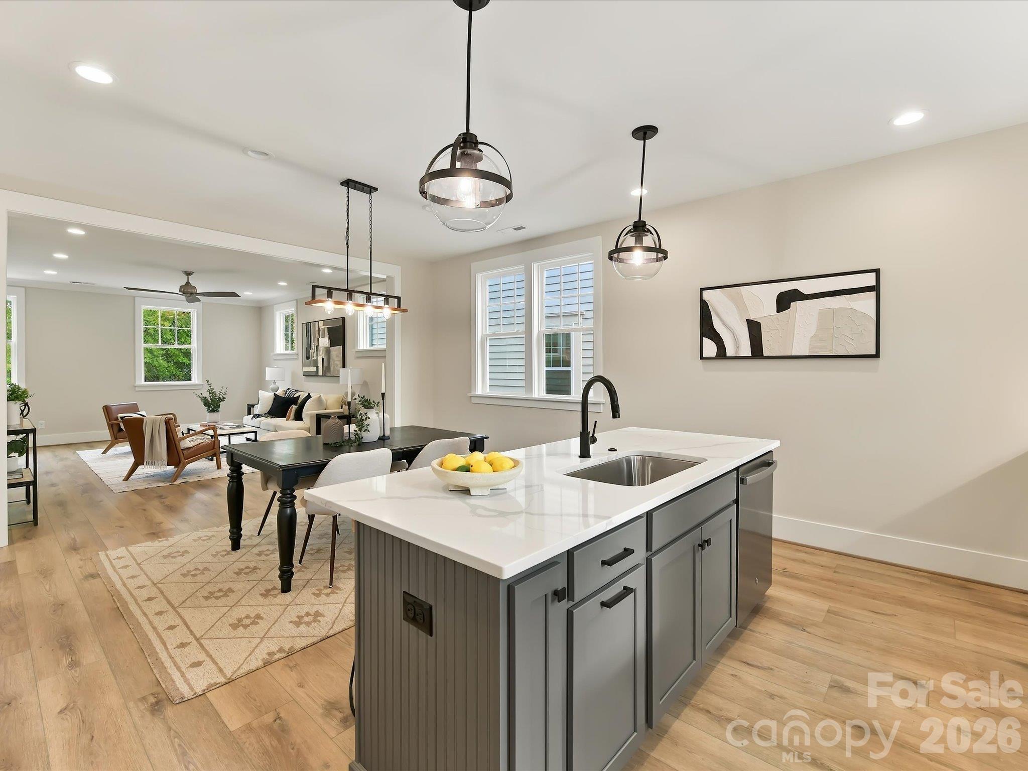 Beautifully designed kitchen featuring modern white cabinetry, quartz countertops, stainless steel appliances, a spacious center island with breakfast bar seating, and an open flow into the dining and living areas. - 225 Davidson Gateway Drive, Davidson
