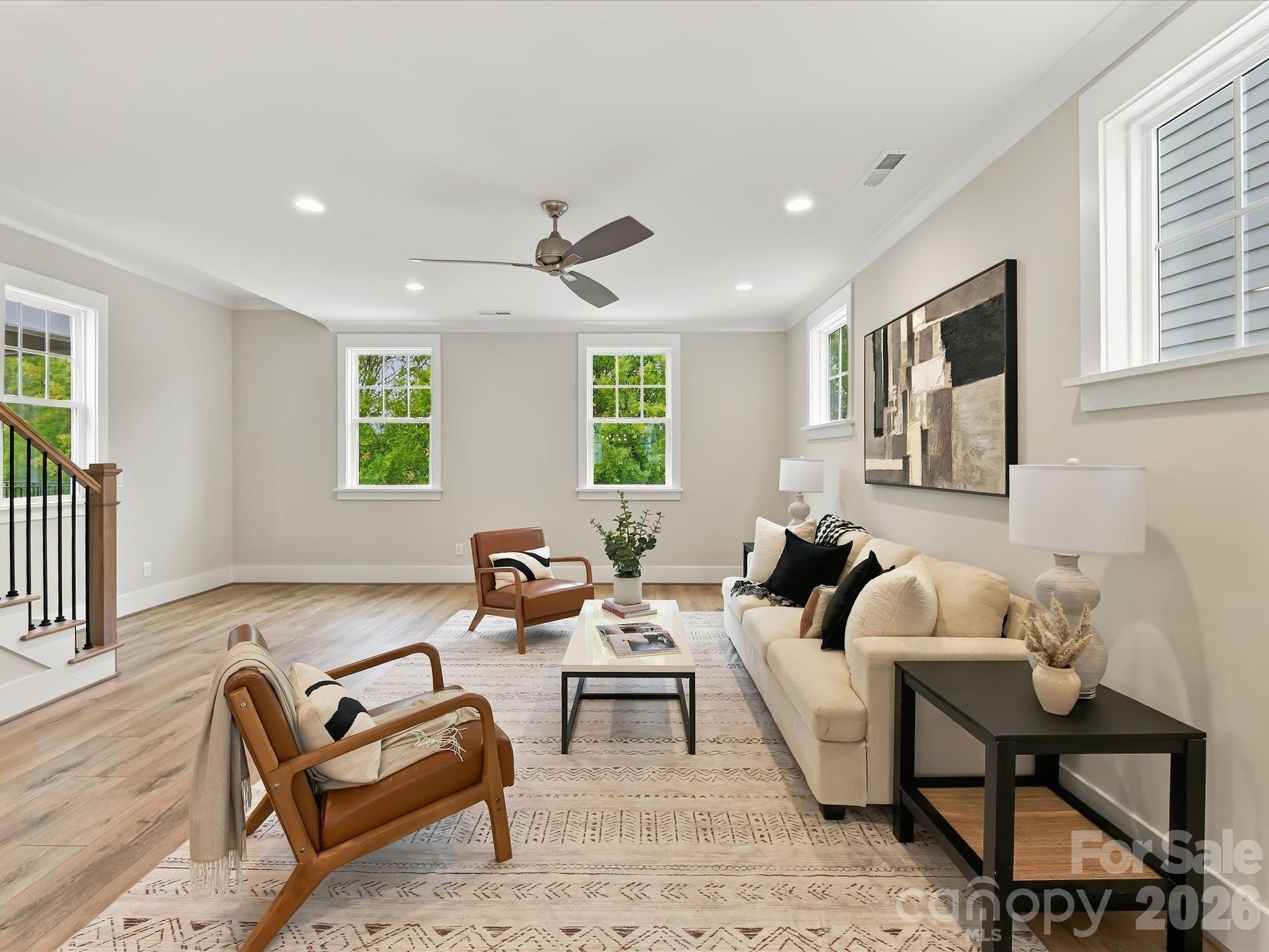 Bright and spacious great room featuring beautiful LVP flooring, abundant natural light, a ceiling fan, and an open flow into the dining area and kitchen. - 225 Davidson Gateway Drive, Davidson
