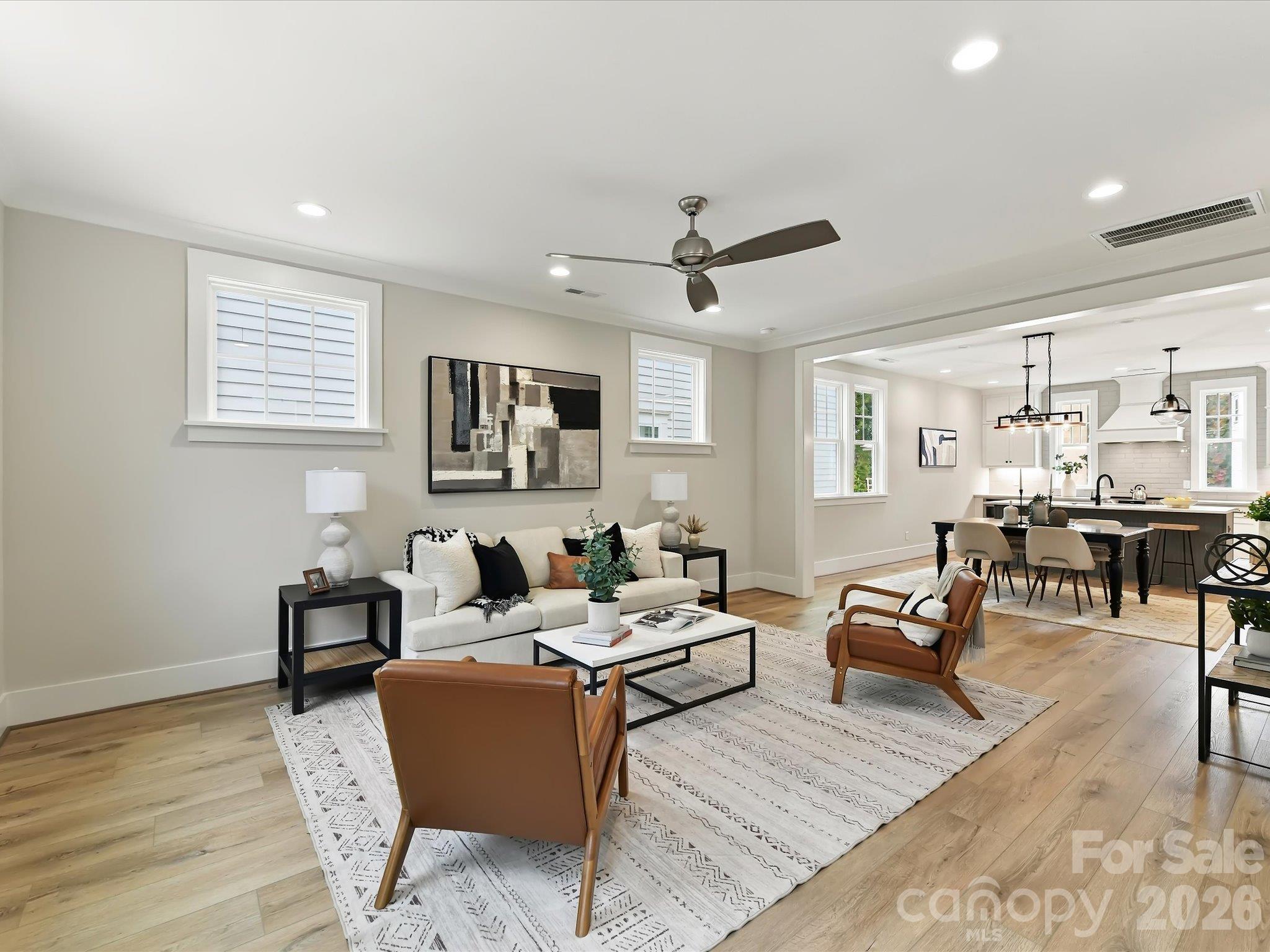 Bright and spacious family room featuring beautiful LVP flooring, abundant natural light, a ceiling fan, and an open flow into the dining area and kitchen. - 225 Davidson Gateway Drive, Davidson