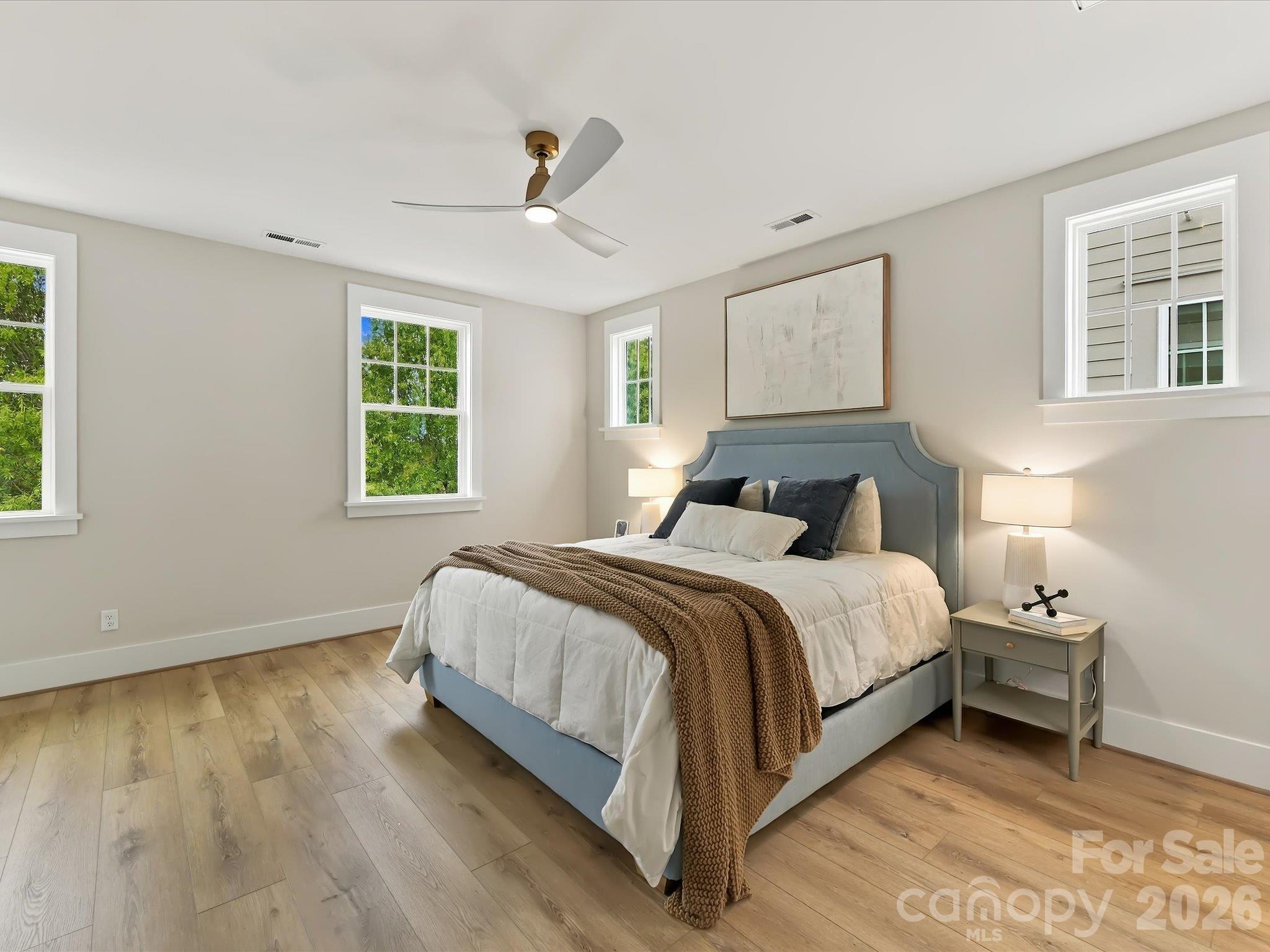 Spacious primary suite featuring beautiful LVP flooring, neutral finishes, modern ceiling fan, abundant natural light, and a private ensuite bath. - 225 Davidson Gateway Drive, Davidson