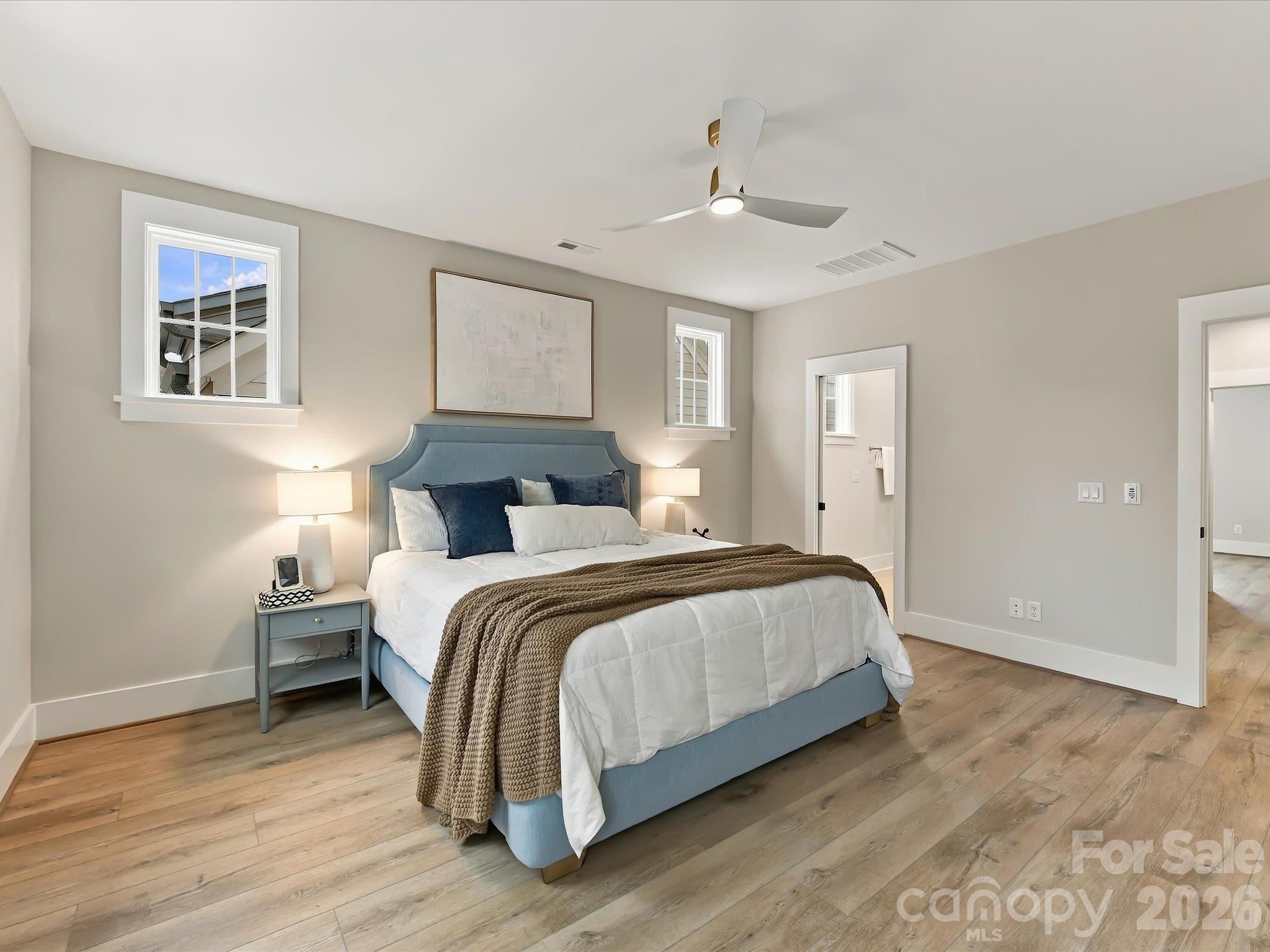 Spacious primary suite featuring beautiful LVP flooring, neutral finishes, modern ceiling fan, abundant natural light, and a private ensuite bath. - 225 Davidson Gateway Drive, Davidson