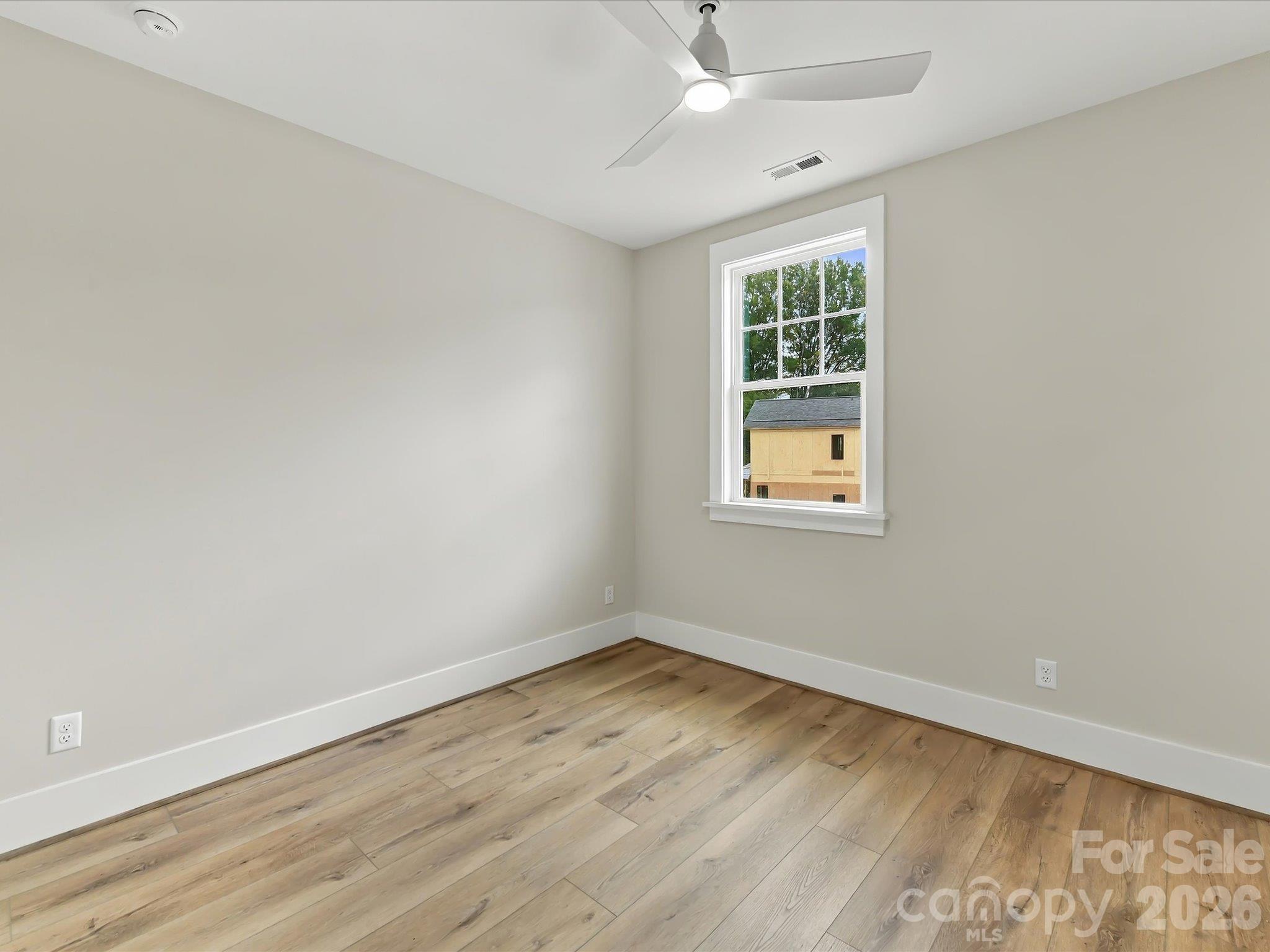 Bright second bedroom featuring LVP flooring, neutral finishes, a modern ceiling fan, ample closet space, and convenient access to a full bath. - 225 Davidson Gateway Drive, Davidson
