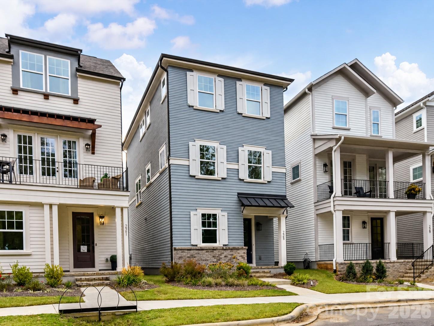 Charming three-story home featuring crisp white shutters, stone accents, and a welcoming covered front entrance. - 225 Davidson Gateway Drive, Davidson