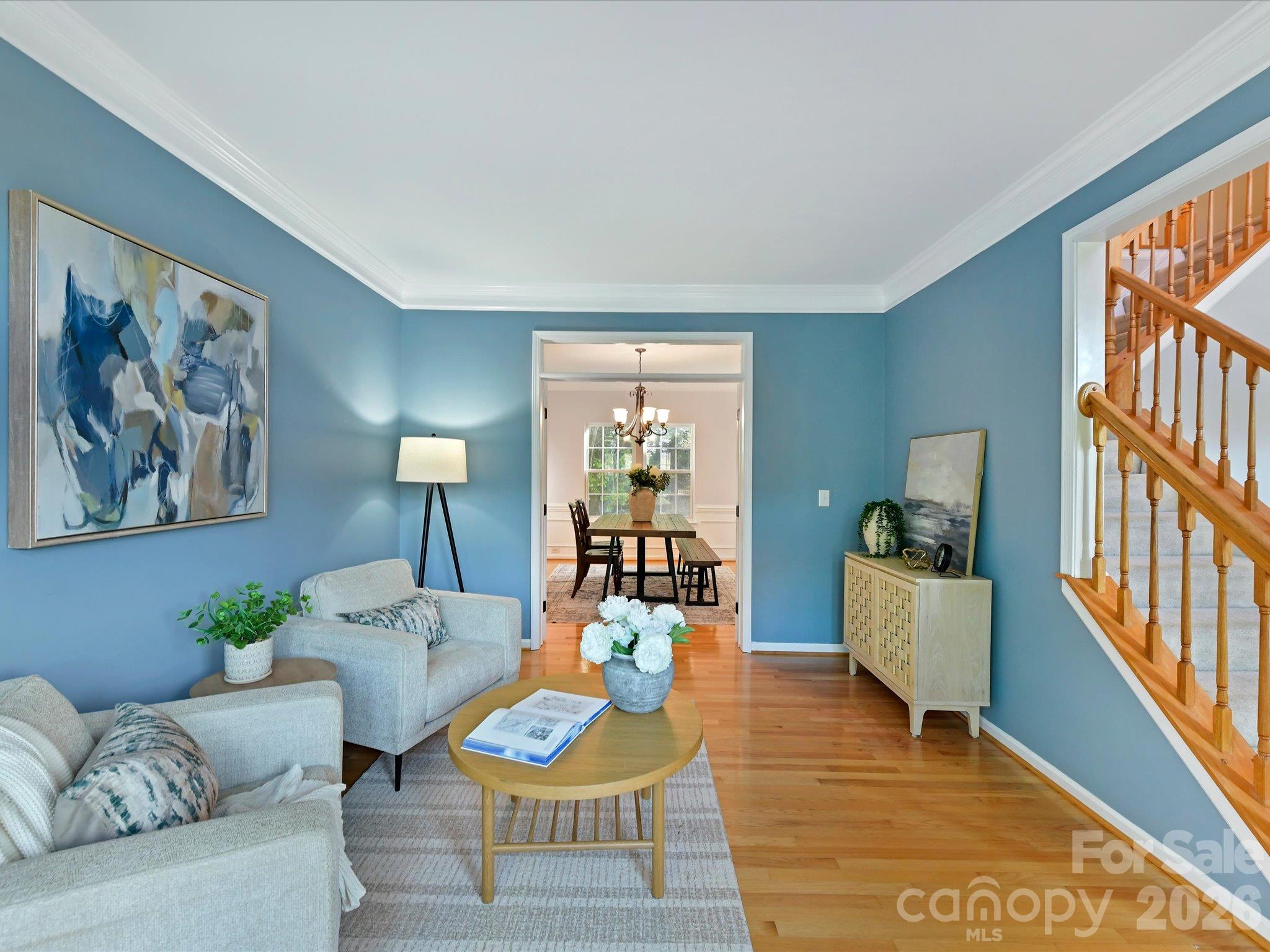 Inviting living room featuring beautiful hardwood floors, elegant crown molding, and a sunlit bay window. - 3819 Waters Reach Lane, Indian Trail