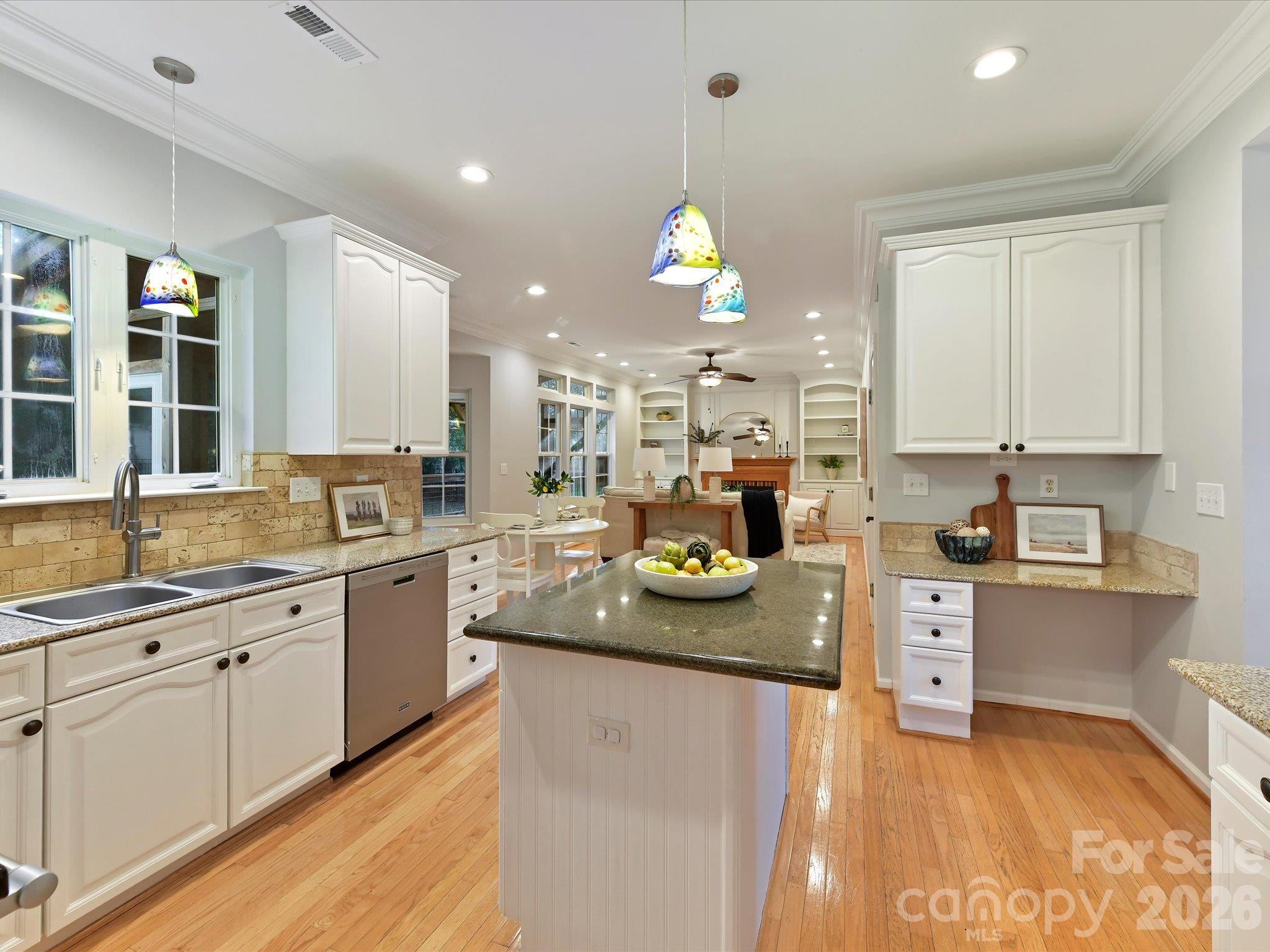 Spacious kitchen featuring modern white cabinetry, granite countertops, stainless steel appliances, a center island, and beautiful hardwood floors. - 3819 Waters Reach Lane, Indian Trail