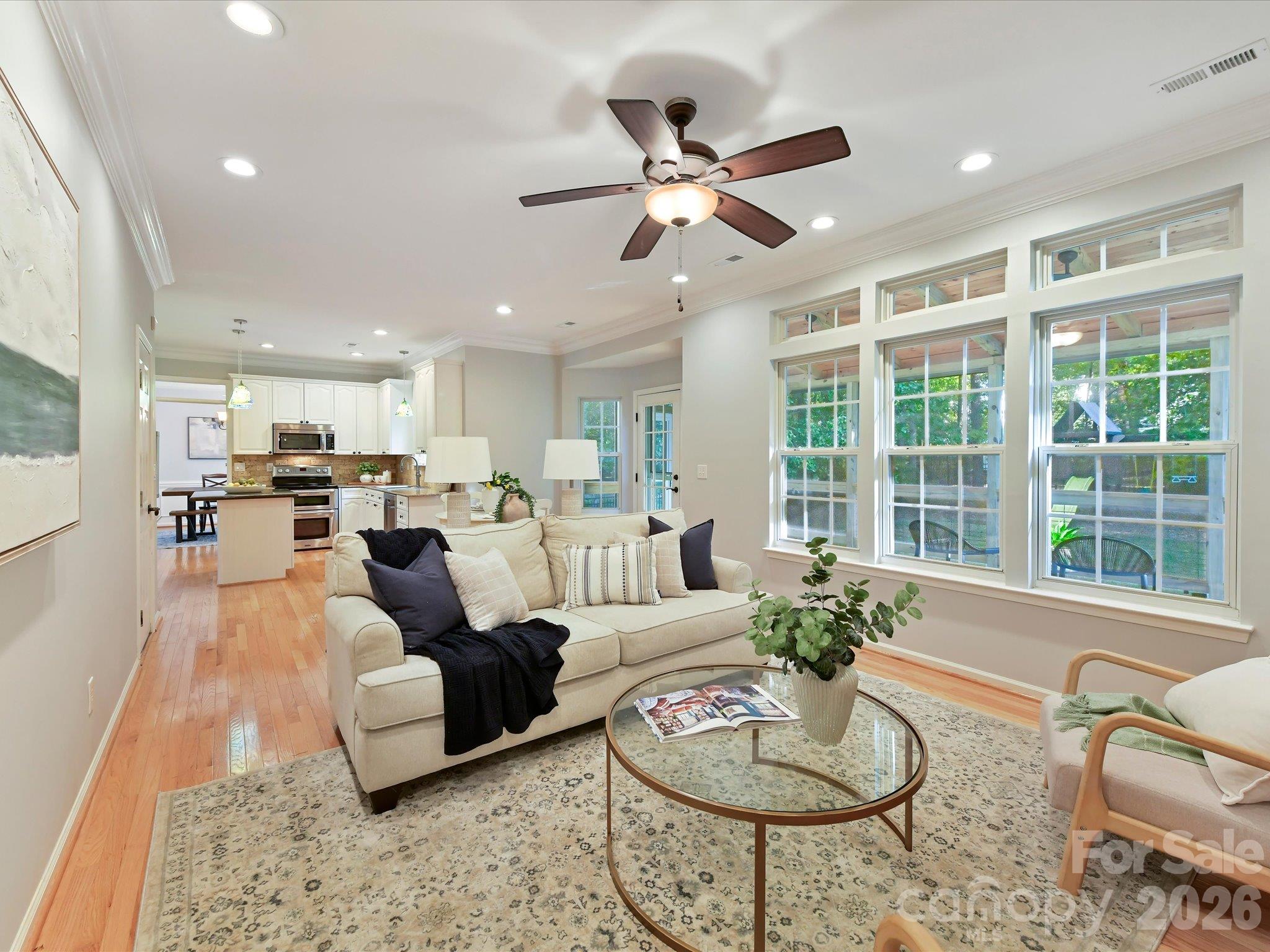 Inviting great room featuring a cozy fireplace, custom built-ins, beautiful hardwood floors, and expansive windows overlooking the backyard. - 3819 Waters Reach Lane, Indian Trail