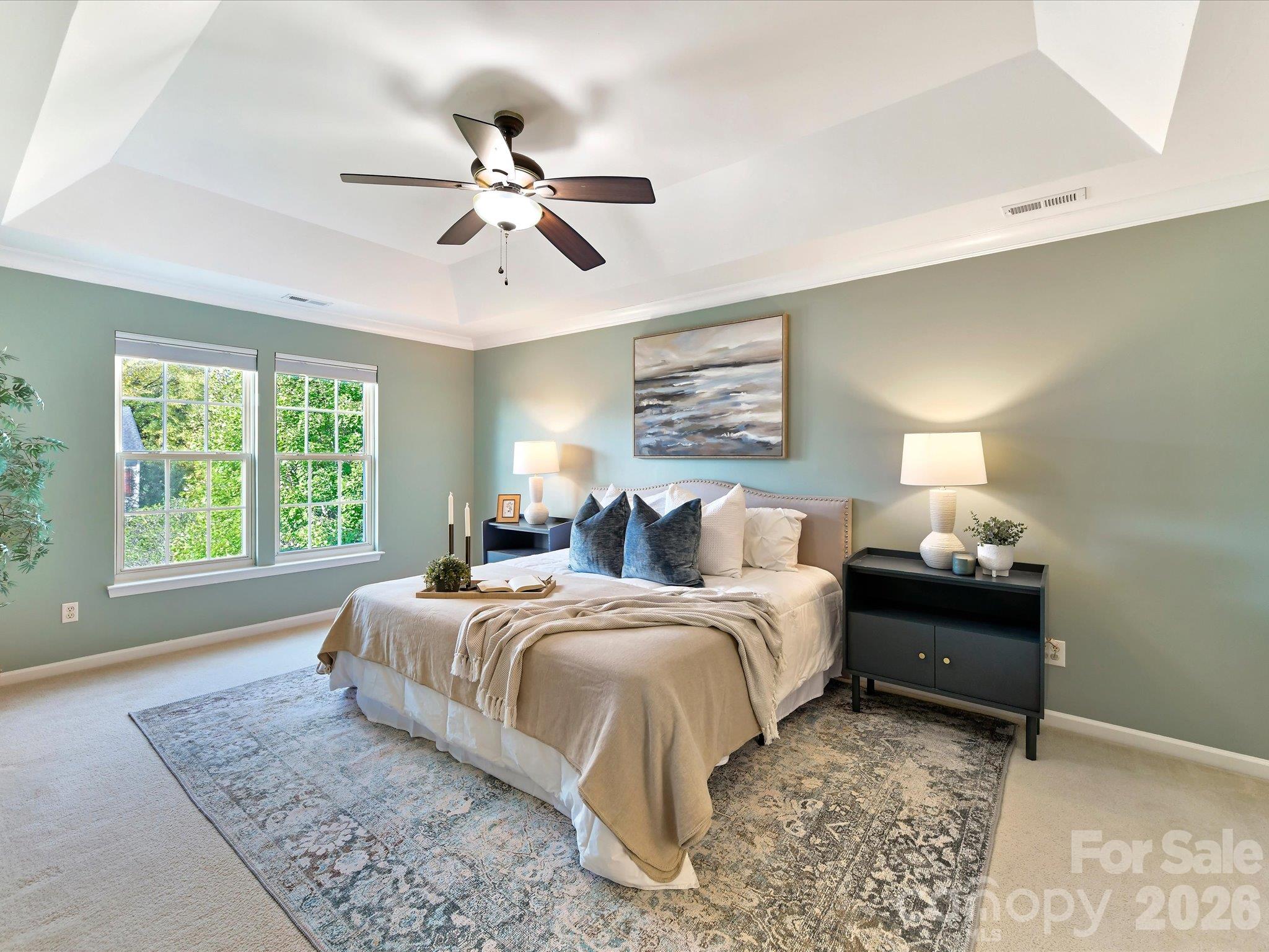 Spacious primary suite featuring a tray ceiling, soothing wall colors, abundant natural light, and a private ensuite bath. - 3819 Waters Reach Lane, Indian Trail