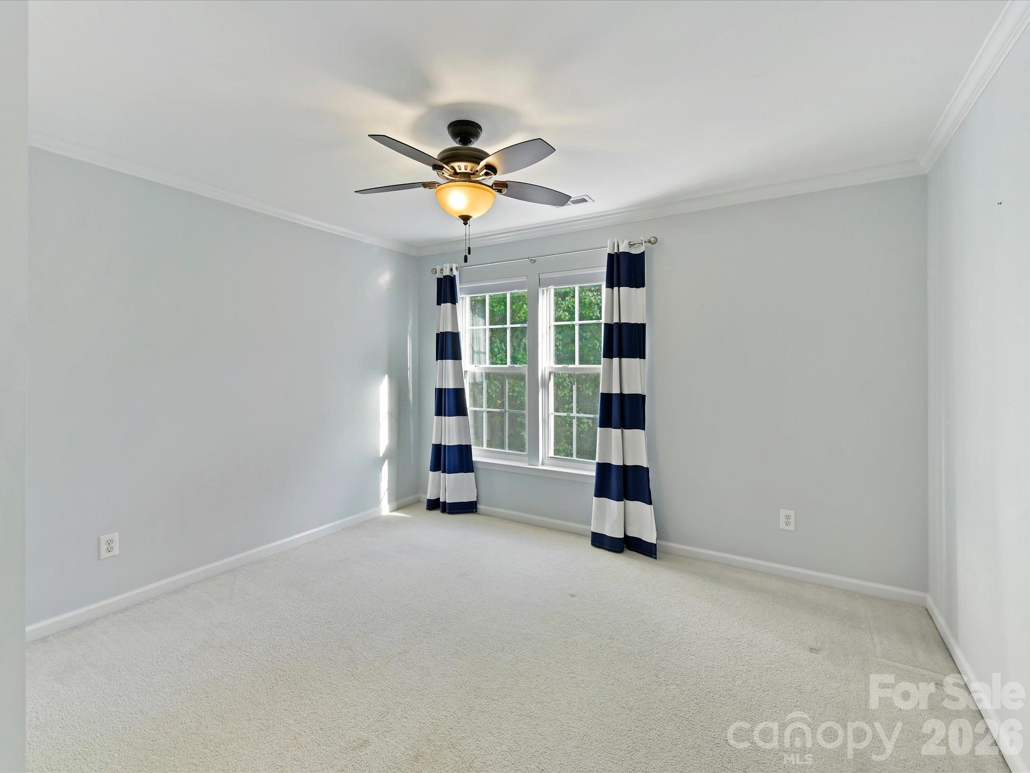 Spacious third bedroom featuring soft carpeting, neutral wall colors, crown molding, a ceiling fan, and large windows offering natural light. - 3819 Waters Reach Lane, Indian Trail