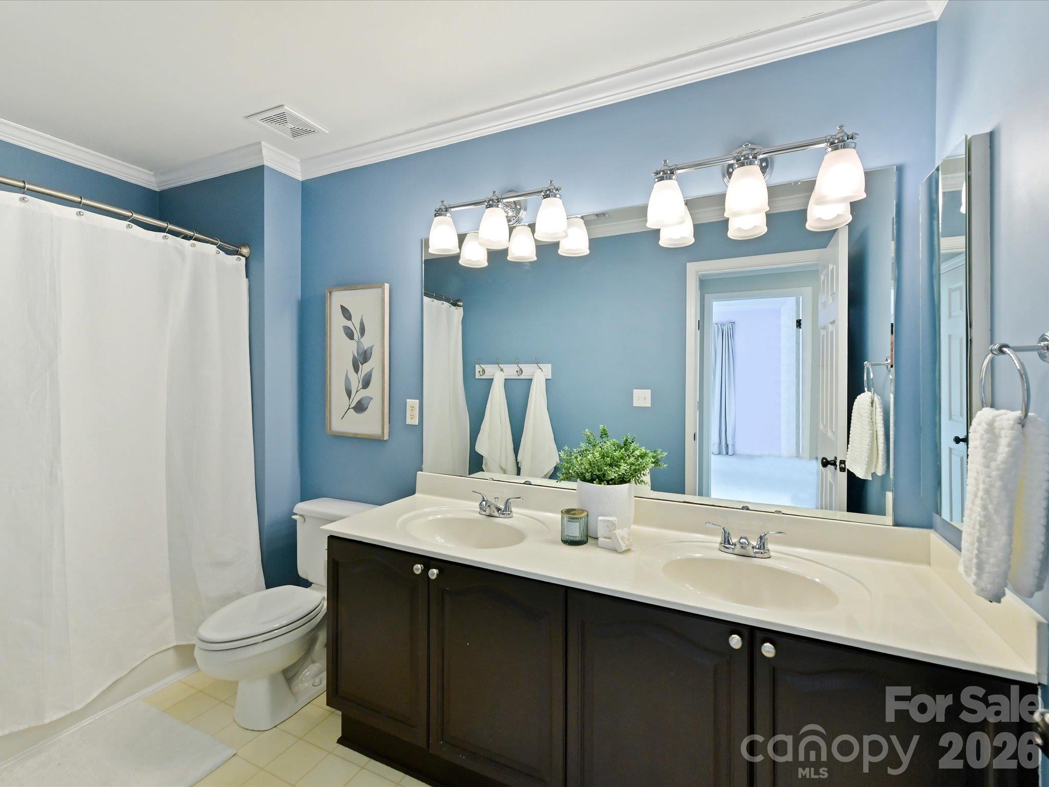 Bright full bath featuring a double-sink vanity, dark wood cabinetry, and a tub/shower combination. - 3819 Waters Reach Lane, Indian Trail