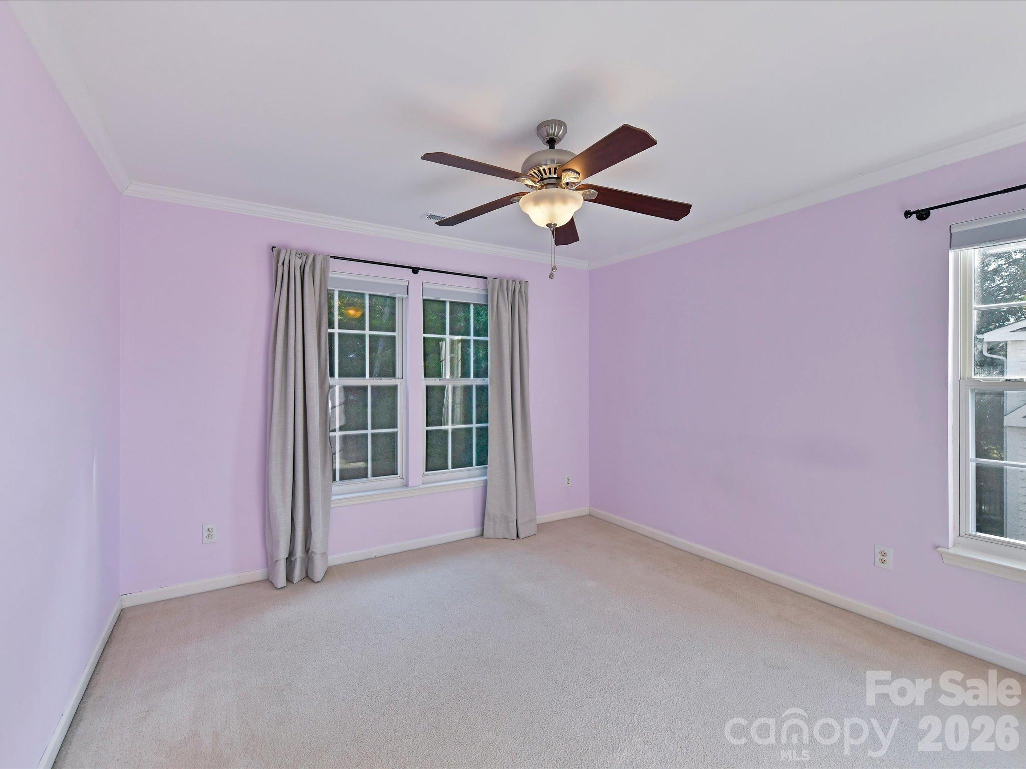 Bright fourth bedroom featuring soft carpeting, crown molding, a ceiling fan, and multiple windows providing natural light. - 3819 Waters Reach Lane, Indian Trail