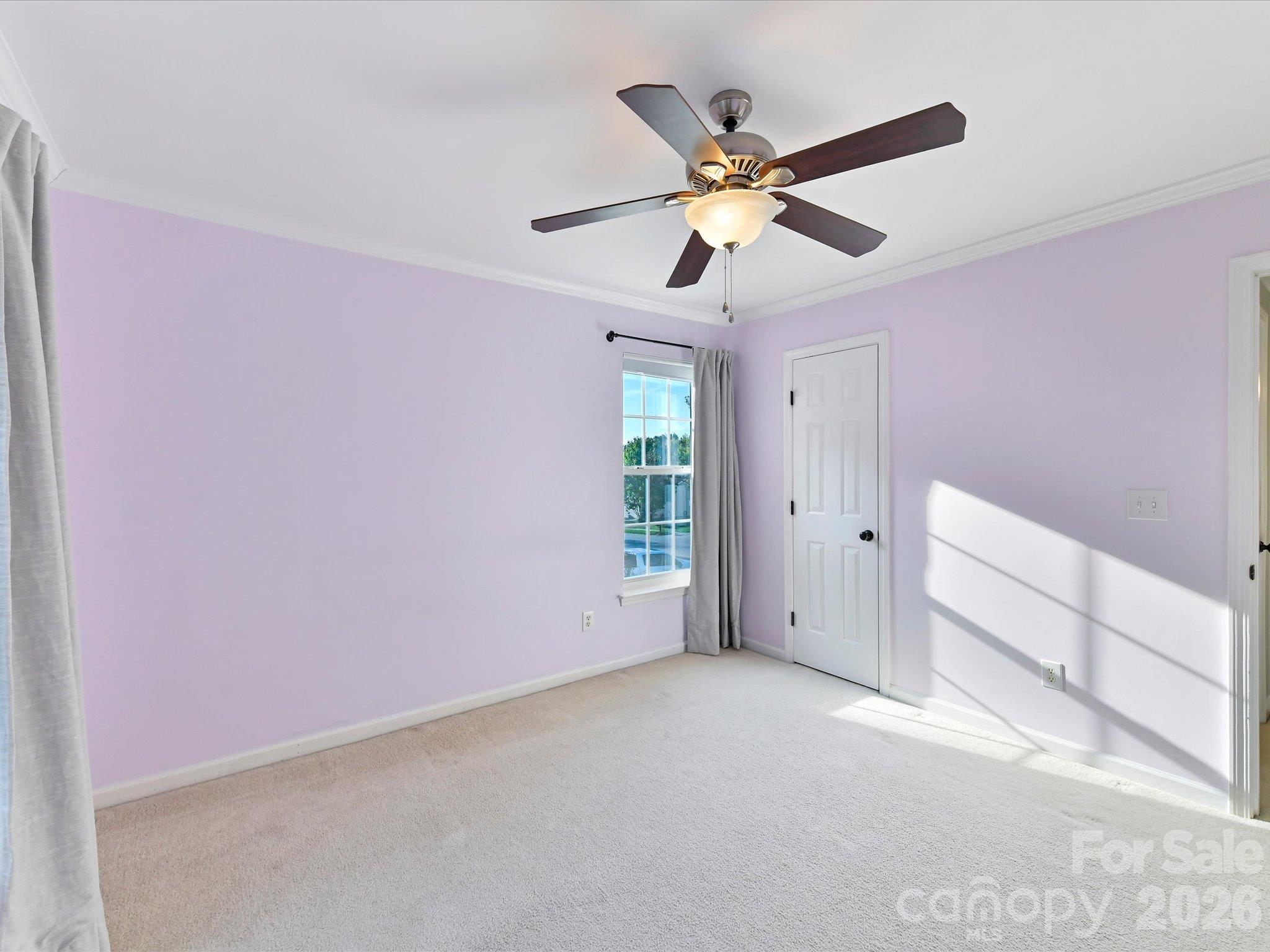 Bright fourth bedroom featuring soft carpeting, crown molding, a ceiling fan, and multiple windows providing natural light. - 3819 Waters Reach Lane, Indian Trail