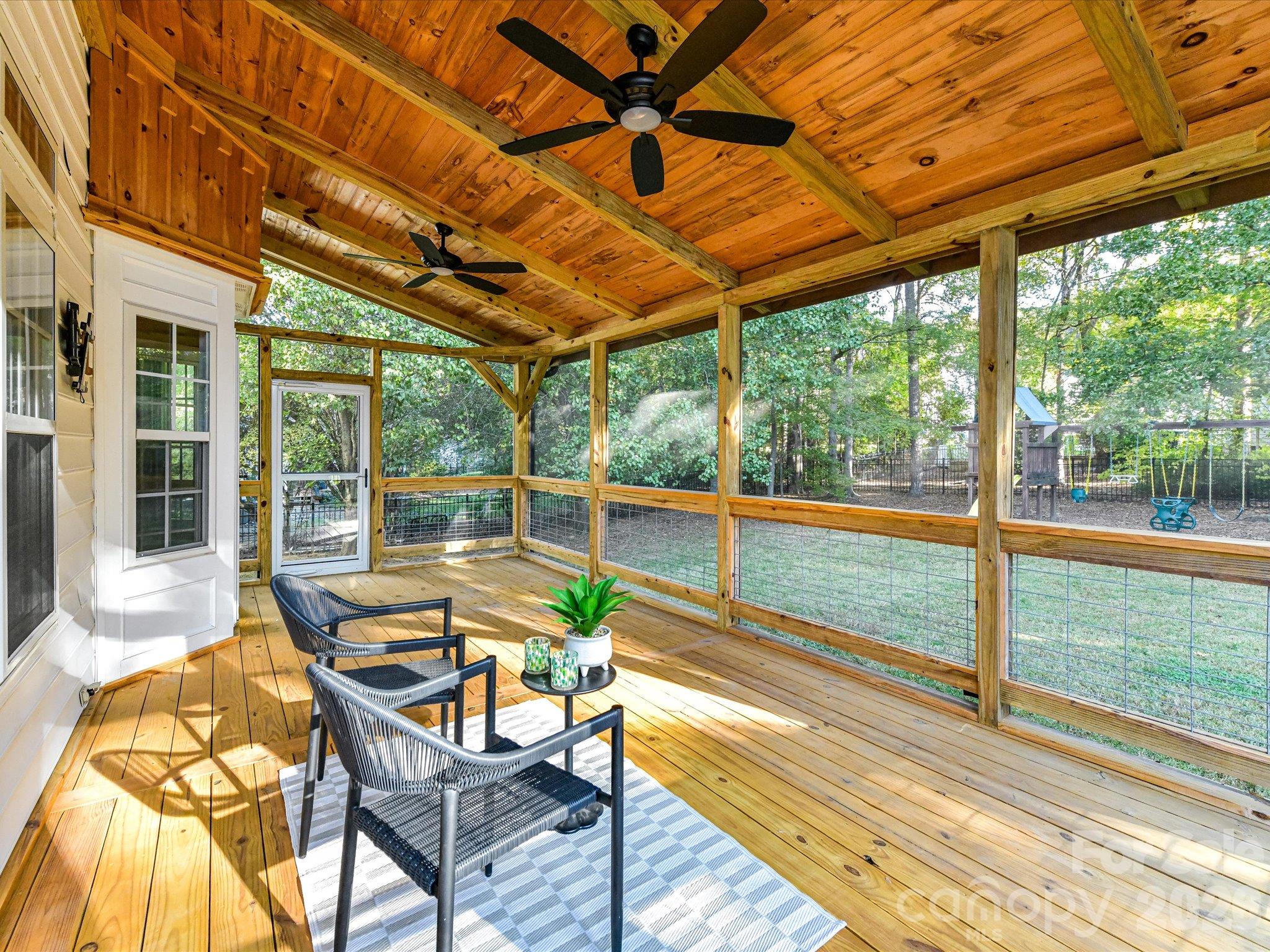 Inviting screened porch featuring a beautiful wood-paneled ceiling, ceiling fans, spacious seating area, and peaceful views of the backyard. - 3819 Waters Reach Lane, Indian Trail