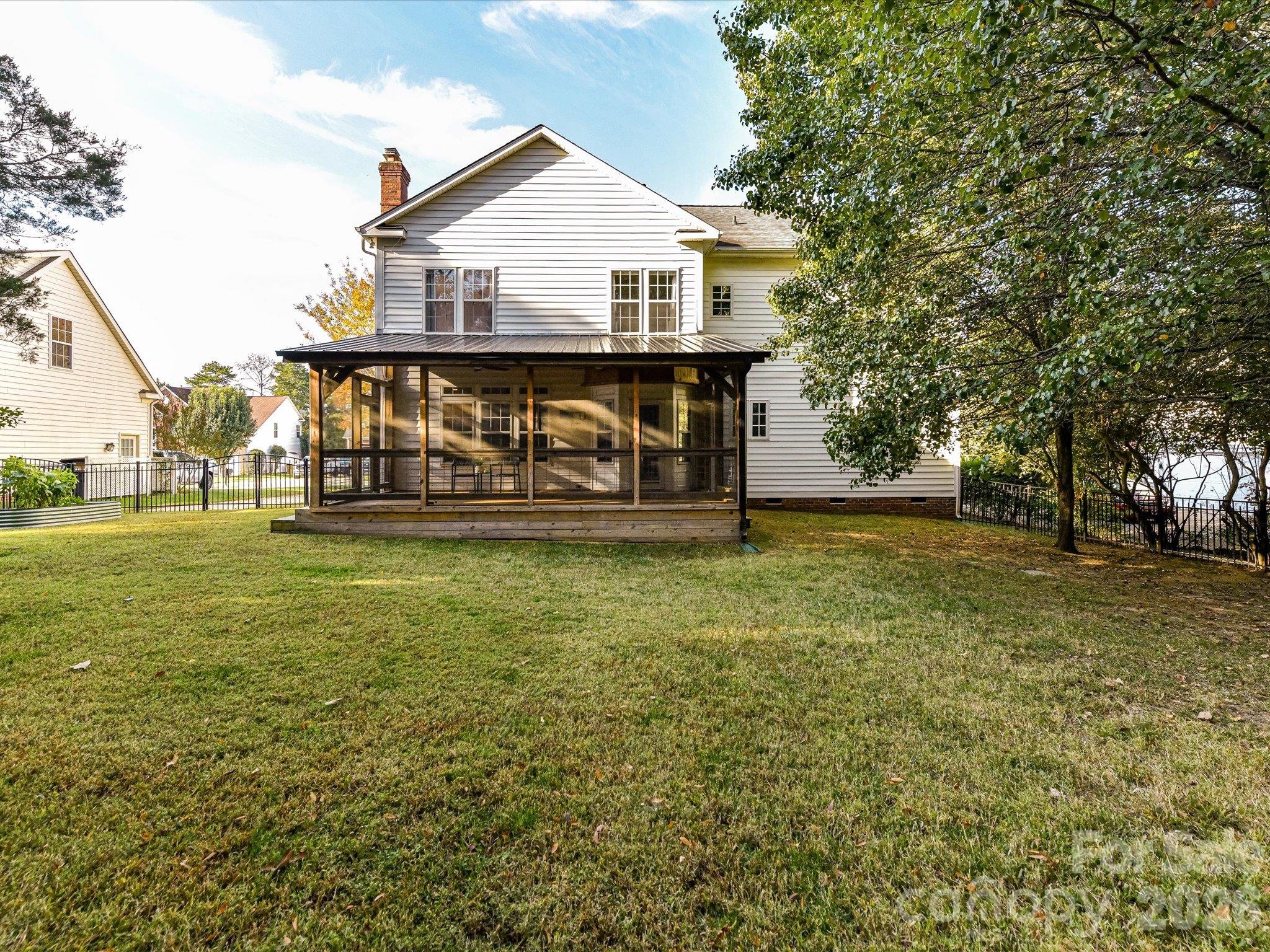 Spacious, tree-lined backyard featuring a fenced lawn, children's playset, and plenty of room for outdoor activities and relaxation. - 3819 Waters Reach Lane, Indian Trail