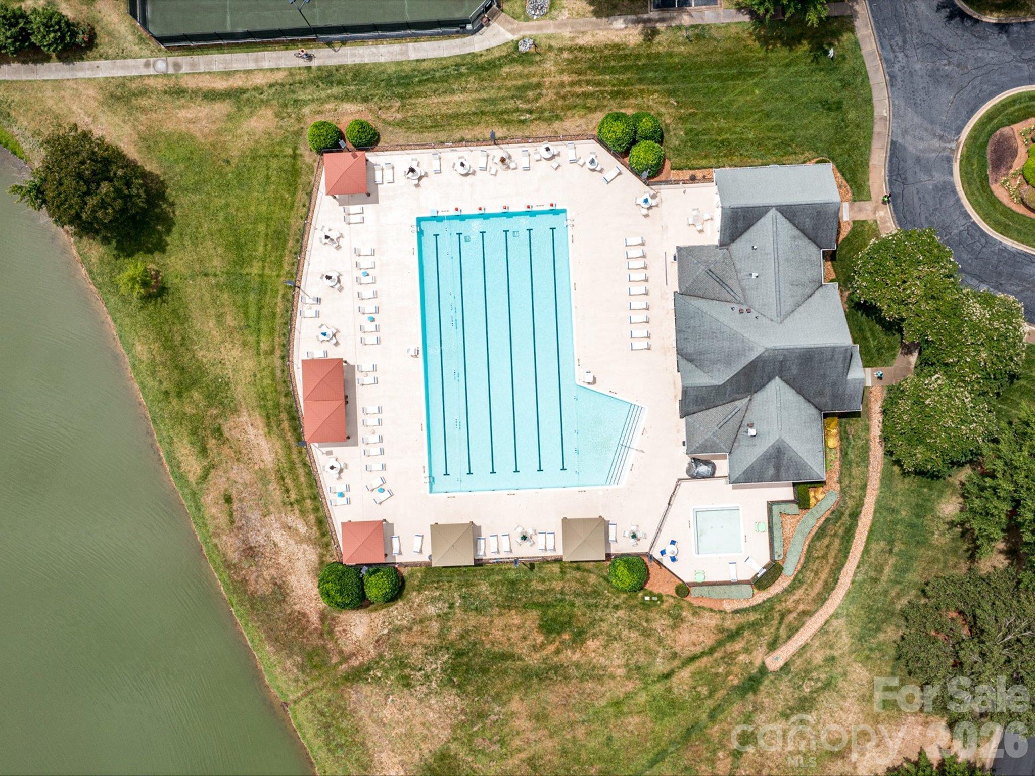 Brandon Oaks community pool featuring spacious swimming lanes, a relaxing poolside deck with lounge chairs and shaded cabanas, and scenic pond views. - 3819 Waters Reach Lane, Indian Trail