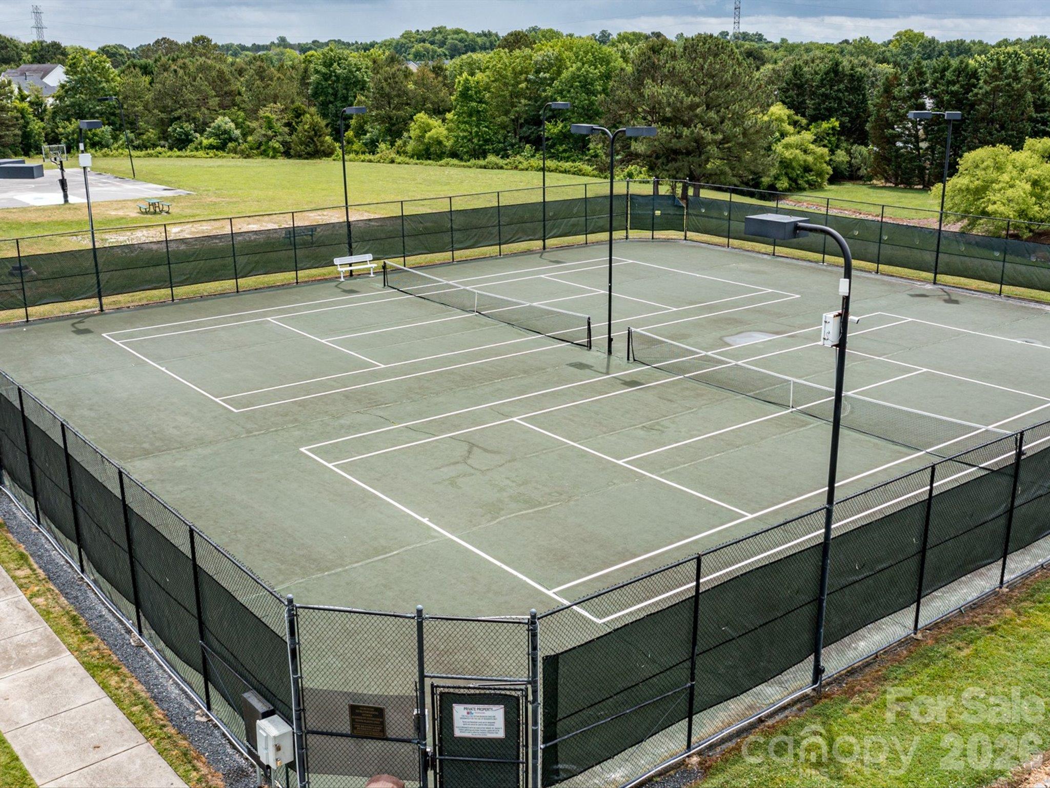 Brandon Oaks community pickleball/tennis courts featuring fenced playing areas, court lighting, and a scenic setting surrounded by lush greenery. - 3819 Waters Reach Lane, Indian Trail