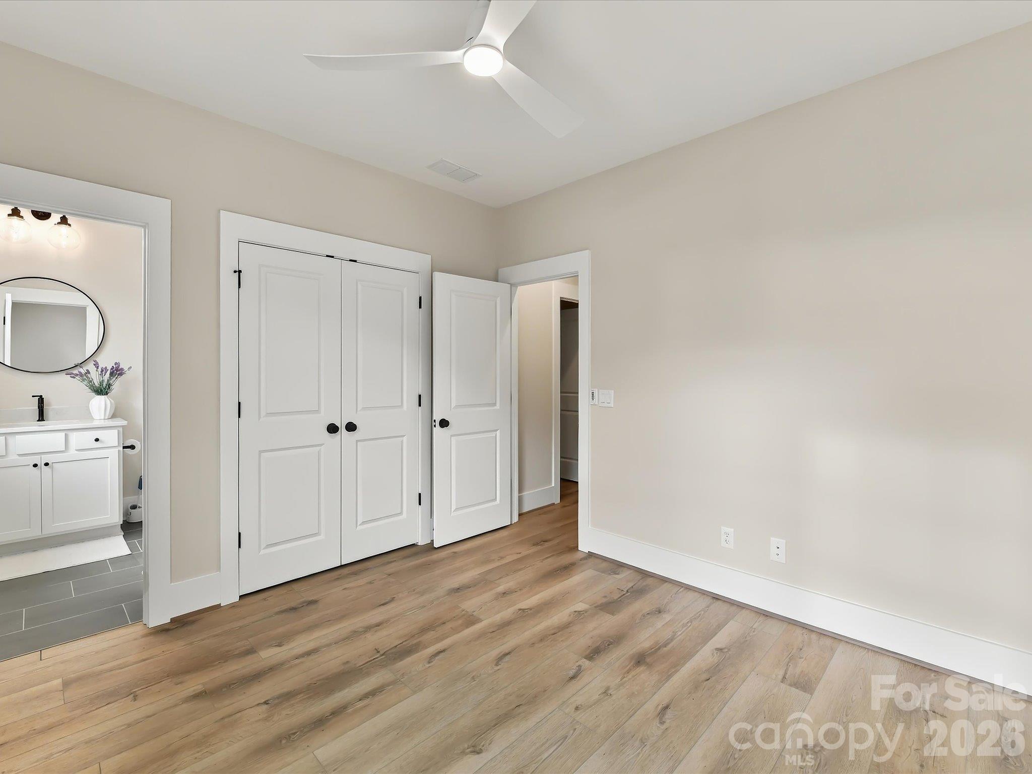 Bright second bedroom featuring LVP flooring, neutral finishes, a modern ceiling fan, ample closet space, and convenient access to a full bath. - 225 Davidson Gateway Drive, Davidson