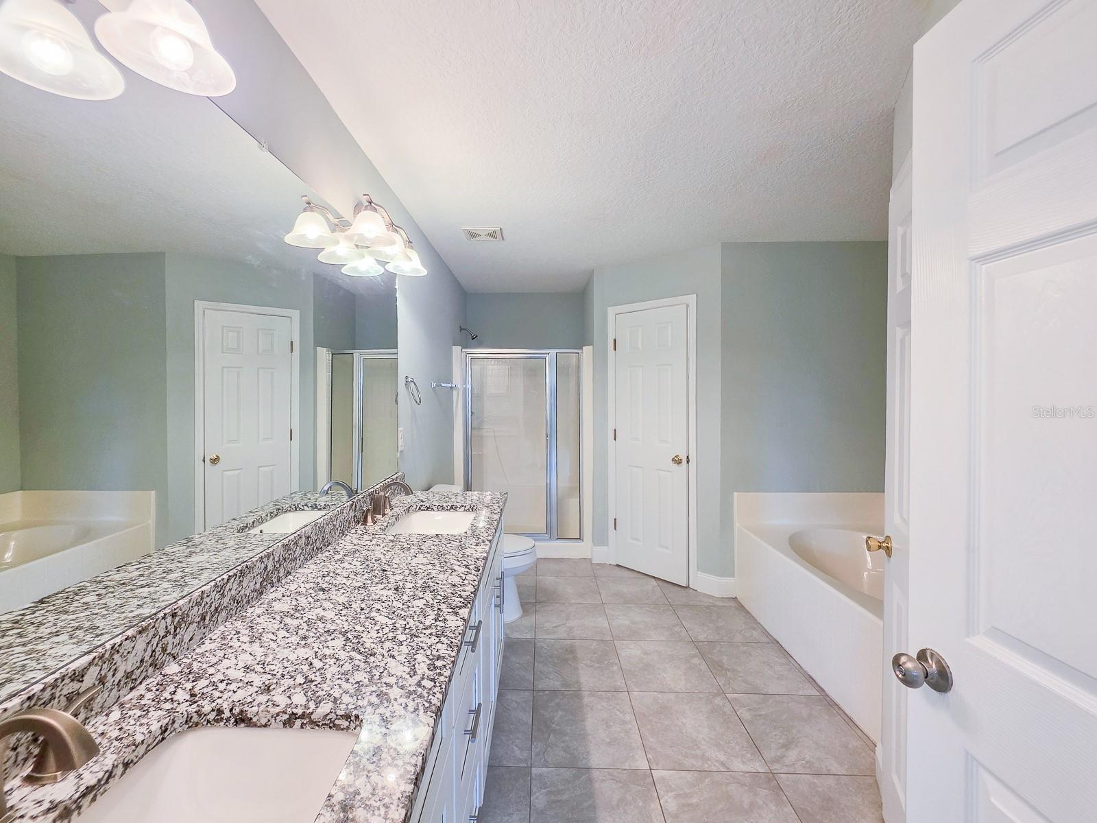 Primary bath with soaking tub, shower, double sinks, granite tops and his and hers closets - 4 LLOWICK CT, PALM COAST