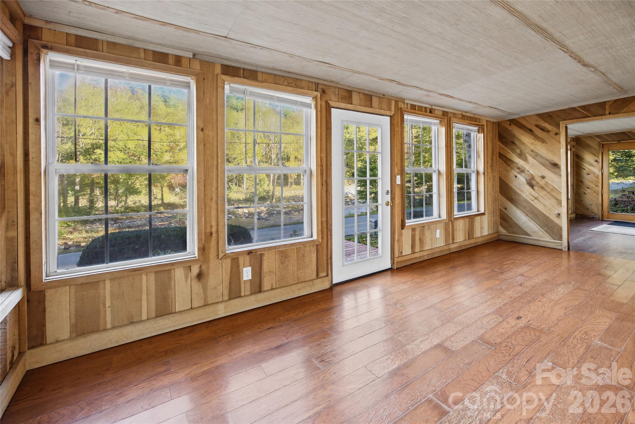 Large sunroom windows frame scenic views of the river and surrounding trees. - 13858 Cruso Road, Canton