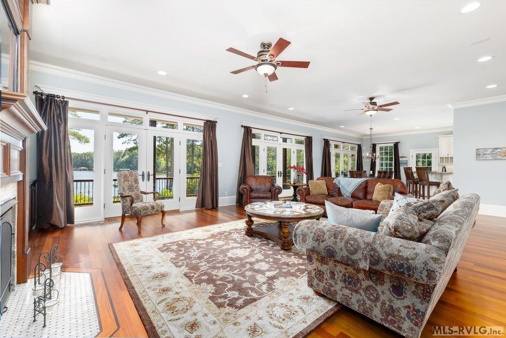 Spacious Traditional Living Room, Comfort while showcasing a beautiful view of Lake Gaston through a wide wall of floor-to-ceiling windows and French Doors. - 381 West Bend Dr., Gasburg VA 23857