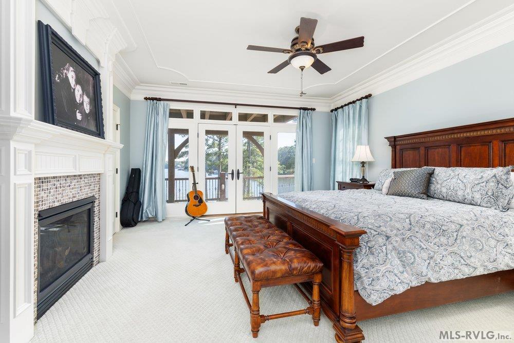 Luxurious Primary Suite, A true sanctuary, featuring a cozy double-sided fireplace and elegant crown molding. French doors open directly to a serene view of Lake Gaston. - 381 West Bend Dr., Gasburg VA 23857