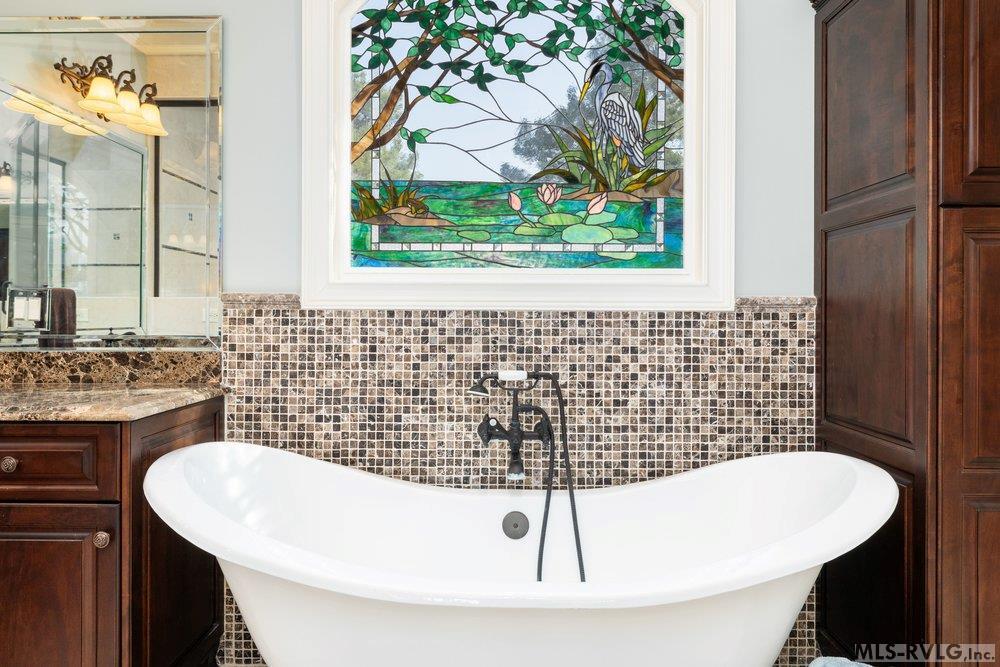 Private Sancturay, Unwind in your freestanding soaking tub, accented by a shimmering mosaic tile backsplash and a vibrant stained glass focal point that brings both artistic flair and natural light. - 381 West Bend Dr., Gasburg VA 23857