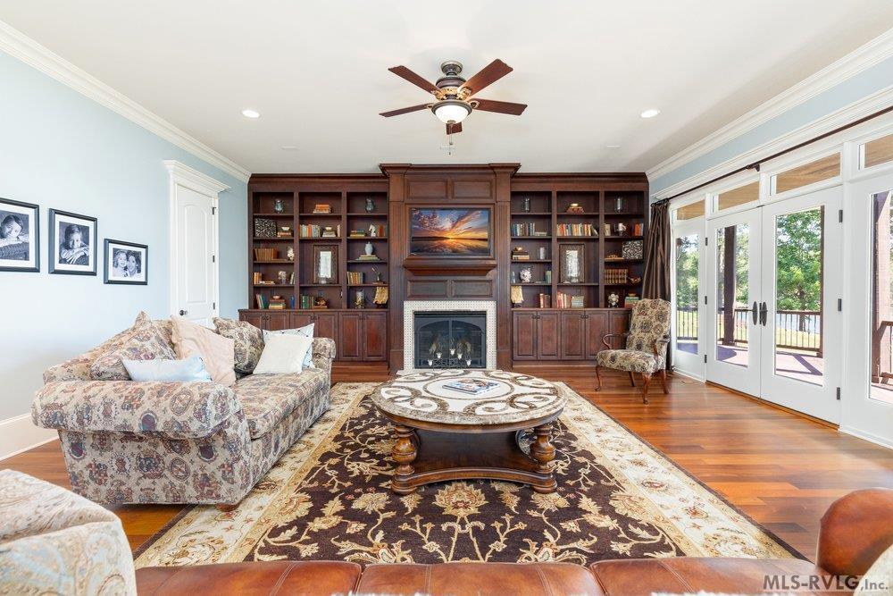 Living Room, The spacious living room is centered around a stunning floor-to-ceiling custom wall unit, featuring wood cabinetry, integrated shelving, and a focal-point fireplace. - 381 West Bend Dr., Gasburg VA 23857